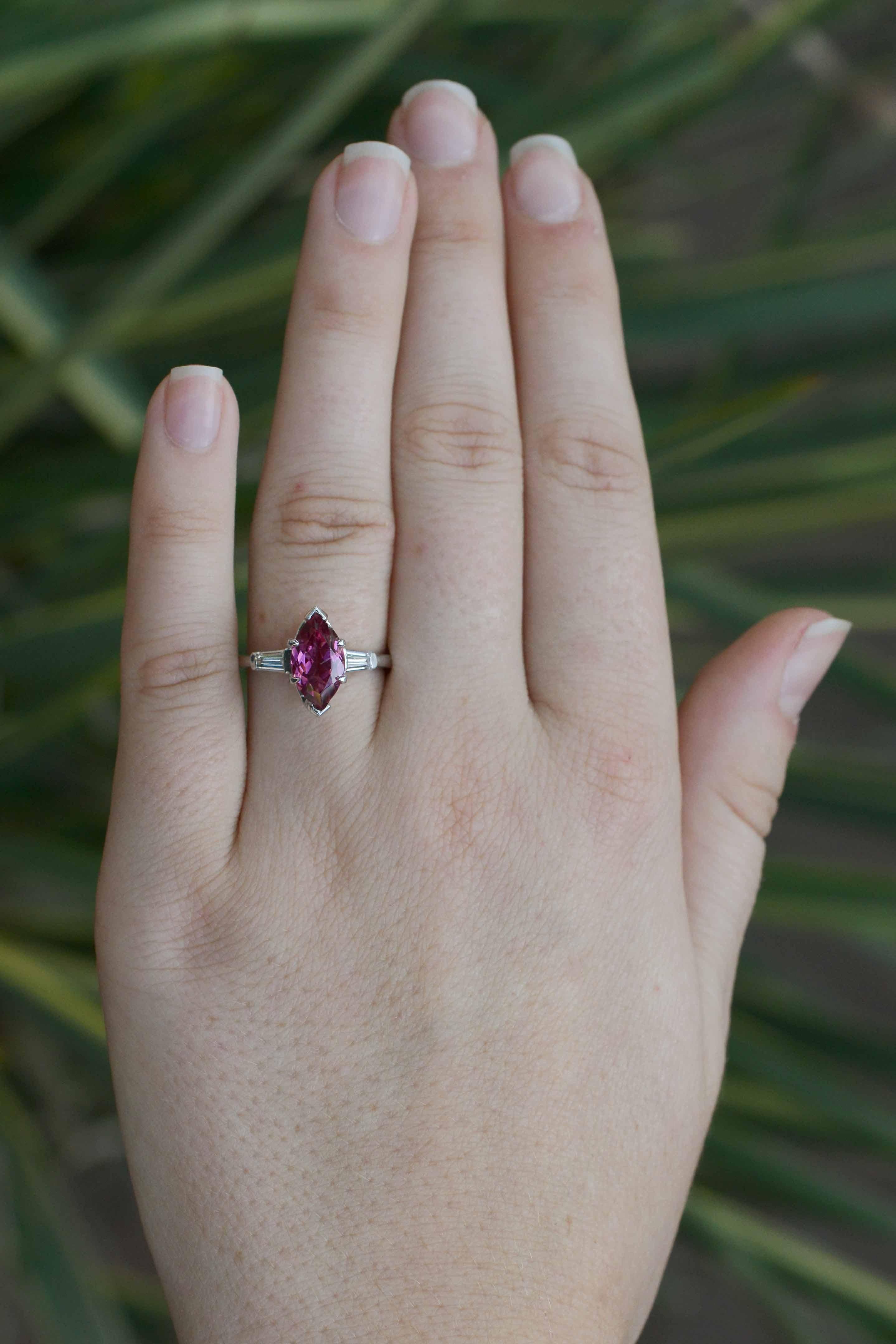 This antique engagement ring presents an attractive reddish pink tourmaline. Although it is uncommon to see a marquise cut colored gemstone, it captures the light strikingly and makes this piece so special. Set in a classic Art Deco mount featuring