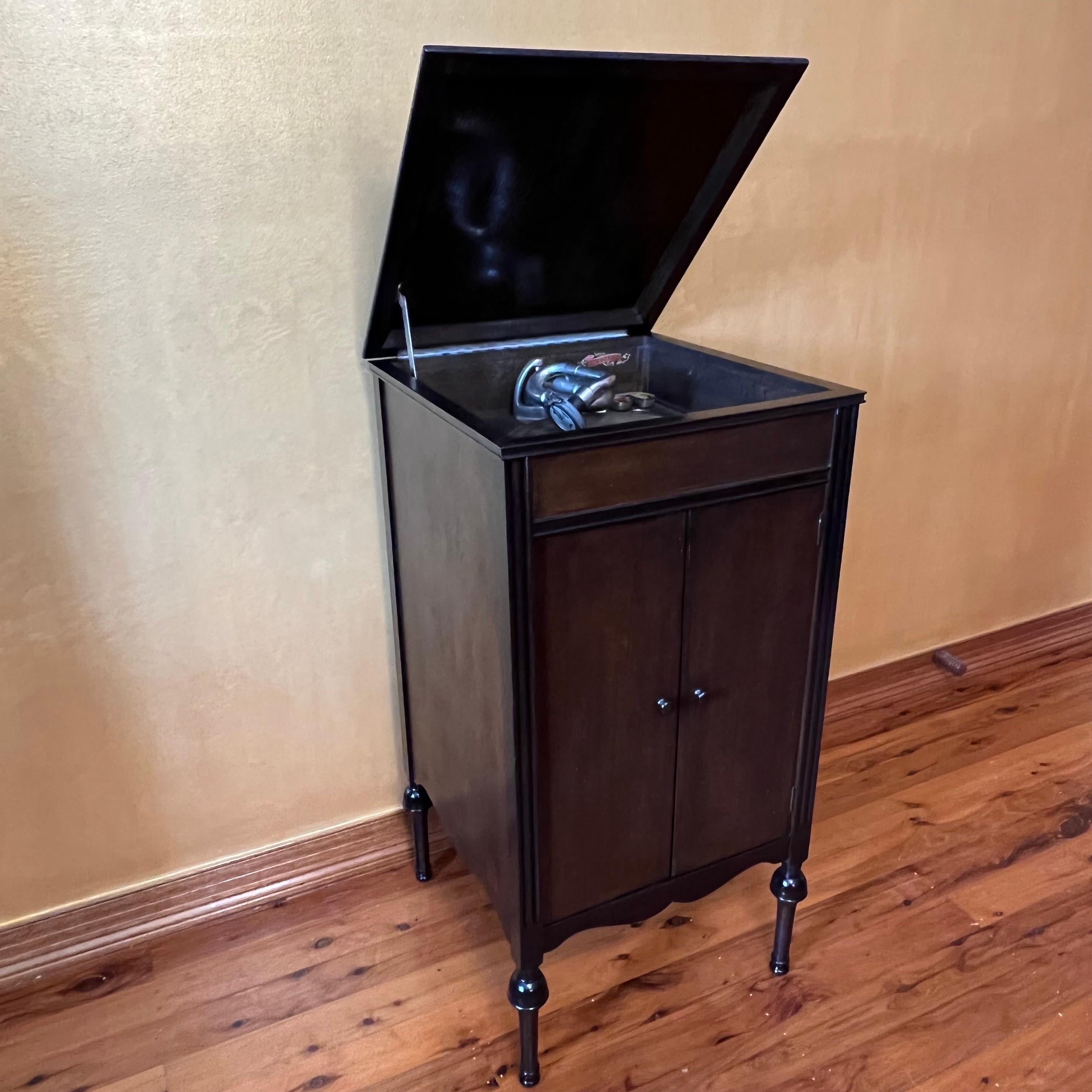In working order, to operate you wind up the handle on the side, the lid can sit up and down the cupboard opens where the speaker is with two shelves to store your recorders, comes with multi pins to change record pin.

Circa: 1920

Material: