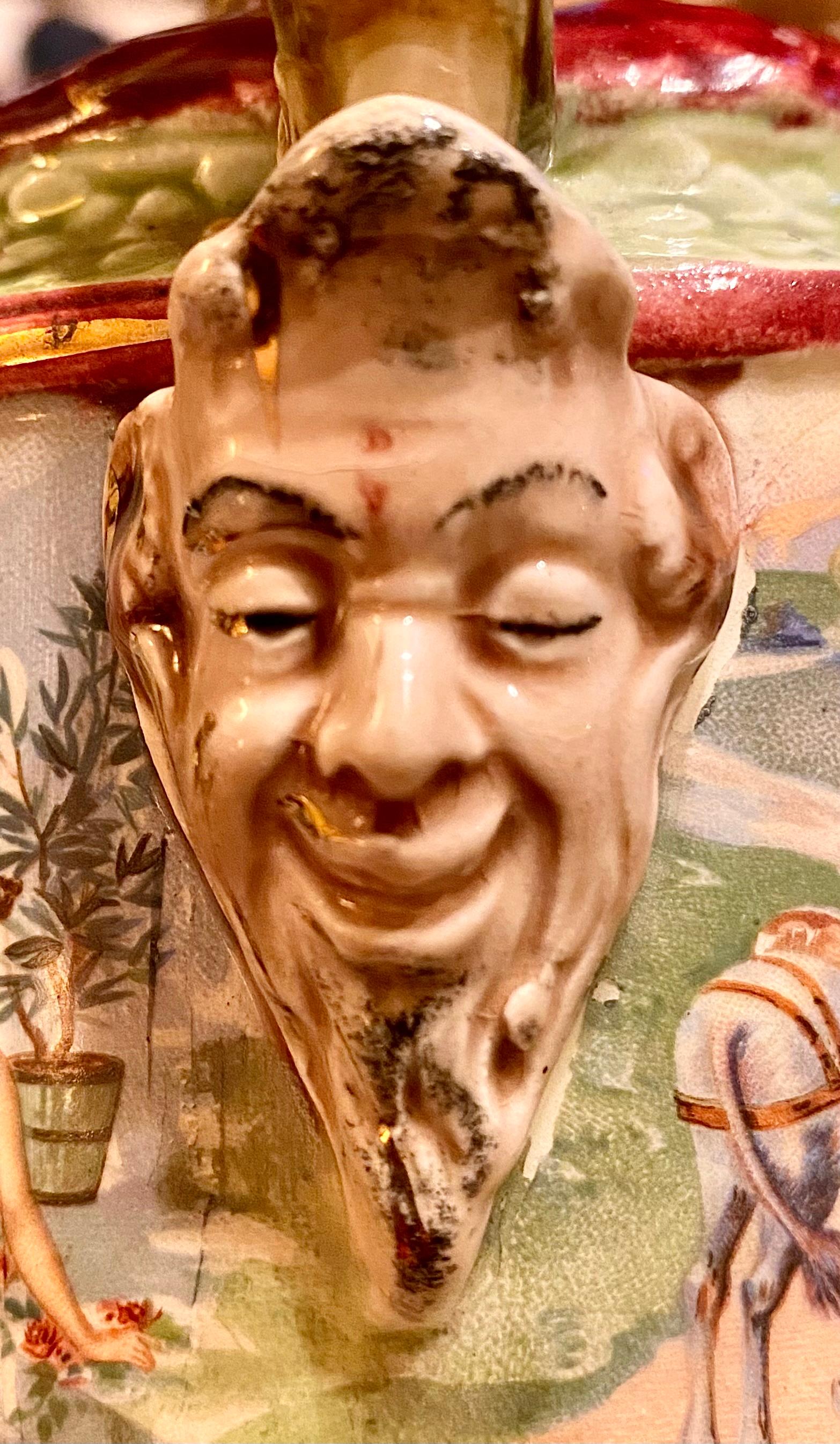 An antique, grand tour, Italian hand painted and transfer ware majolica handled vase with panels depicting Ancient Greek Society, handles in the shape of winged griffin's and grotesque masks mounted on each side. 
Harmoniously blending colors of