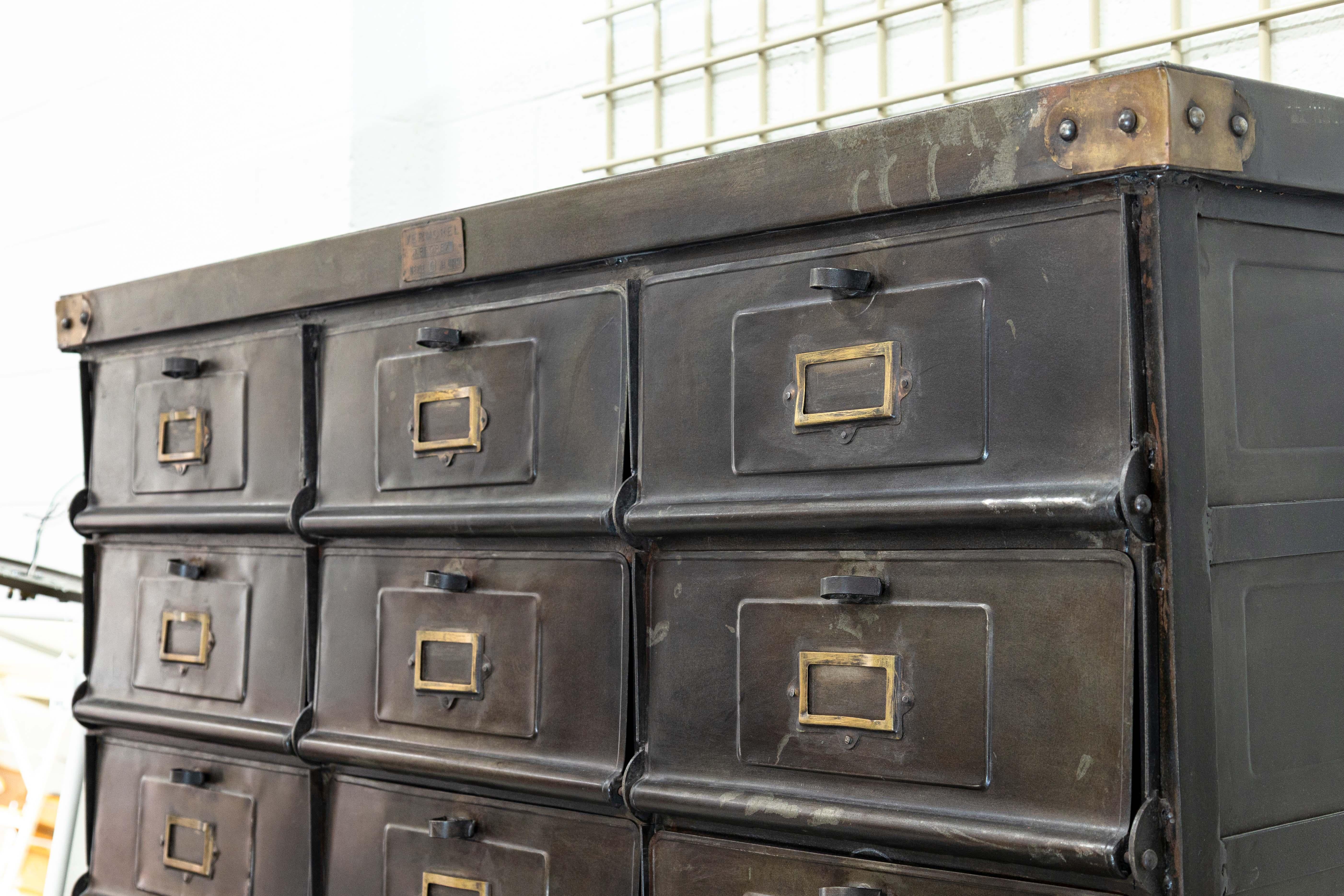 An antique 1920s French steel cabinet. This wonderful industrial cabinet features an outstanding patina to its black steel frame. This piece features 30 identical doors with matching hardware. Each door opens up with a small twisting knob and drops