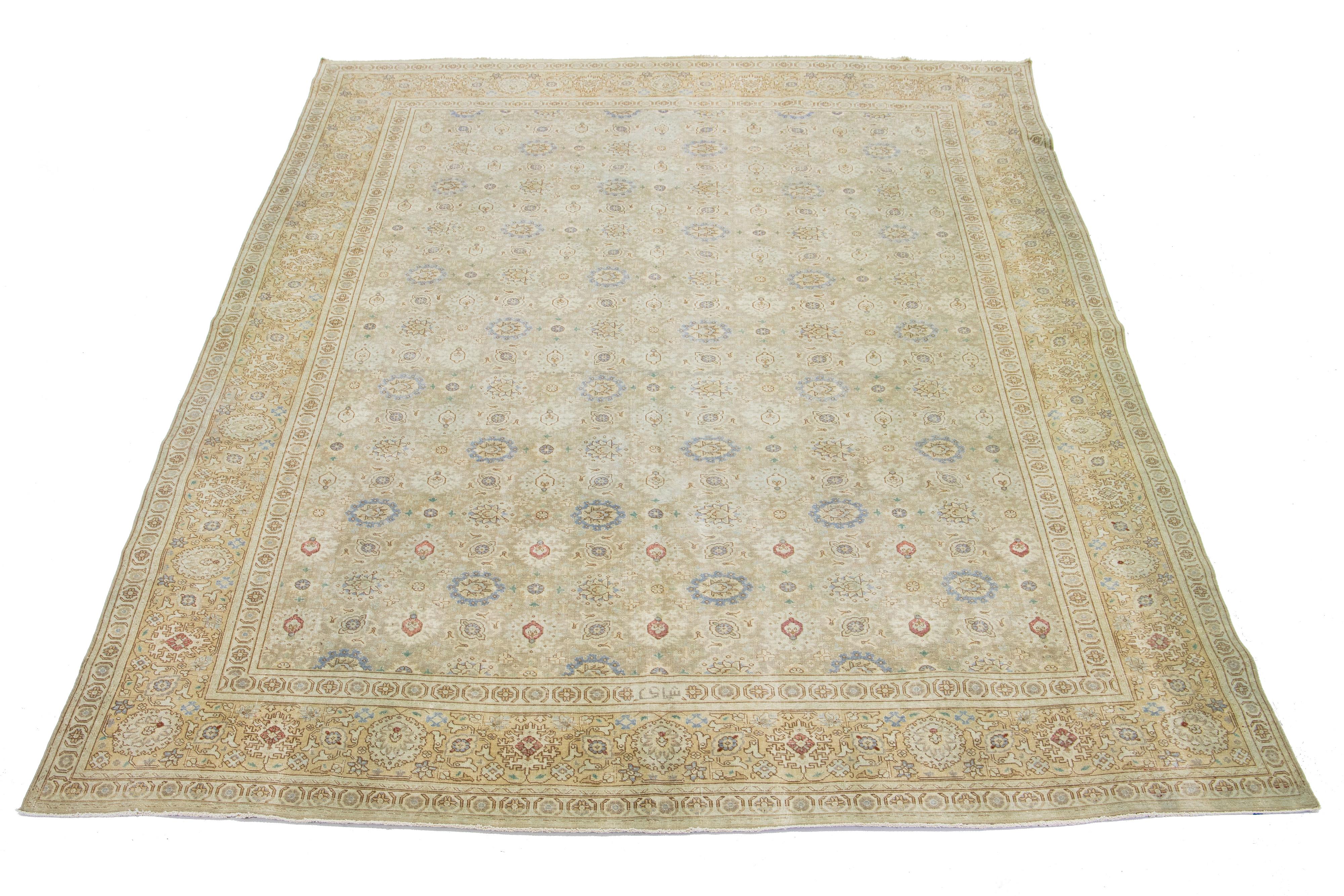A Persian Tabriz wool rug from the 1920s showcases a handcrafted, traditional floral pattern. The design is accentuated by contrasting colors such as beige, green, and blue in the field.

This rug measures 9'4