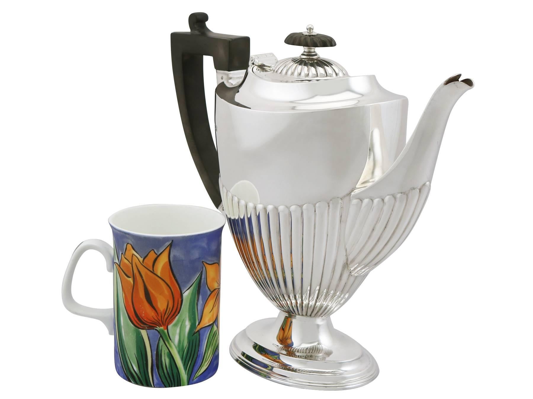 A fine and impressive antique George V English sterling silver coffee pot in the Queen Anne style; an addition to our silver teaware collection.

This fine antique George V sterling silver coffee pot has an oval form onto an oval pedestal foot in