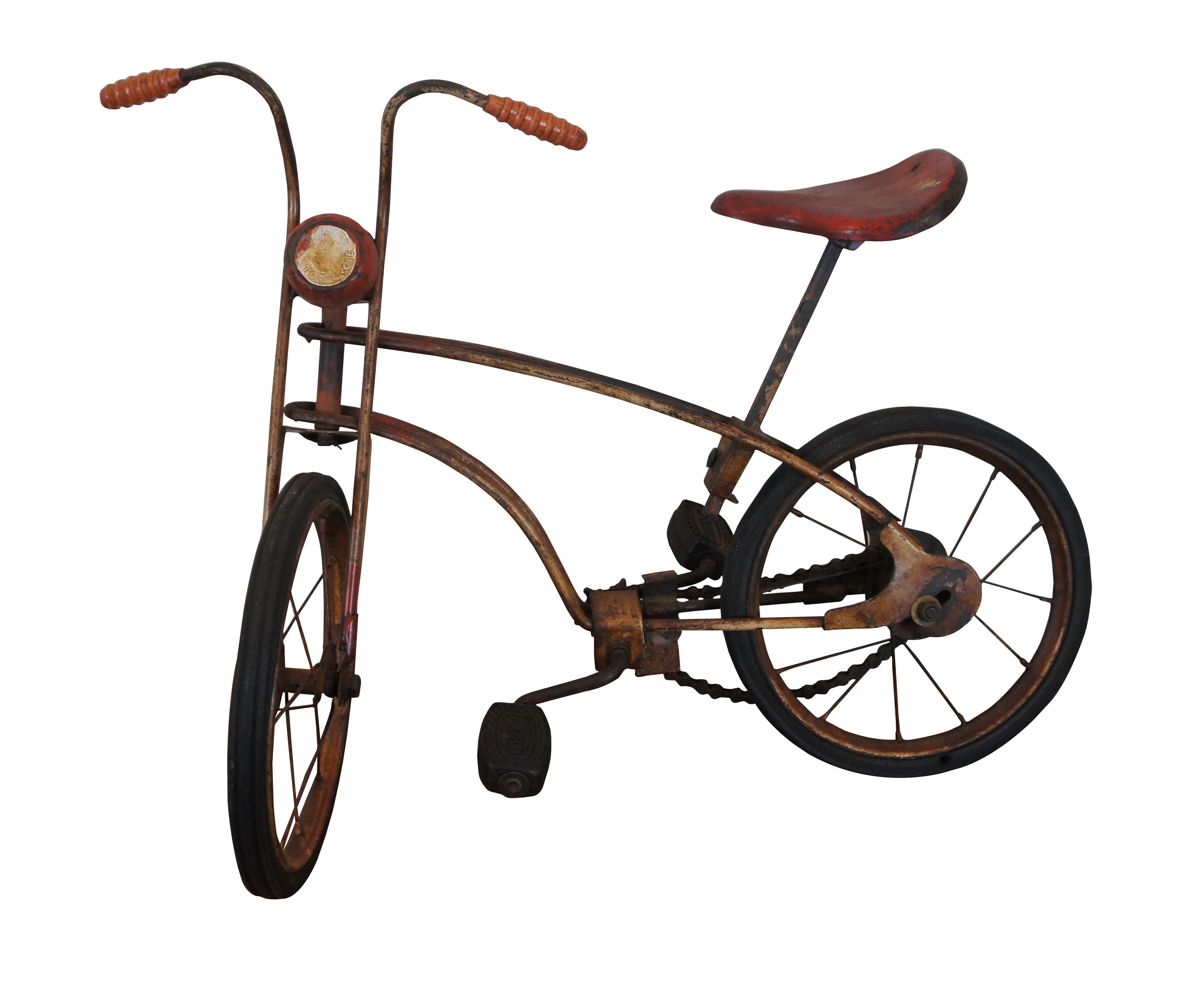 Antique child’s bicycle, the Mobo Tot-Cycle by Sebel Products of England.  Features a well worn steel frame with red and white paint job, rubber tires and foot pedals, textured hand grips and metal saddle seat.  Circa 1926.