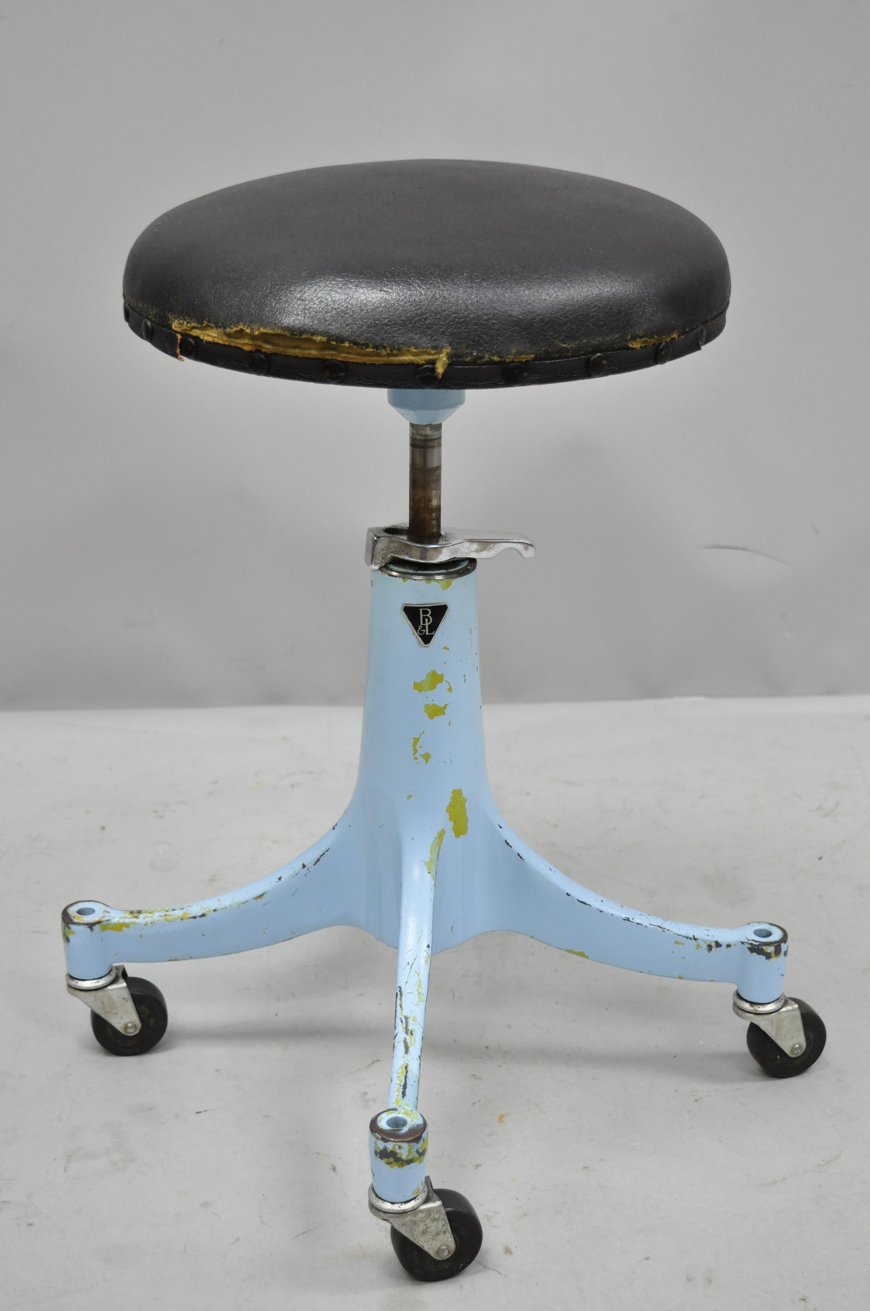 Antique 1930s Bausch & Lomb optical blue industrial medical adjustable stool. Item features adjustable height, cast iron base, wooden seat with black vinyl upholstery, rolling casters, blue finish, original label, very nice antique item, quality