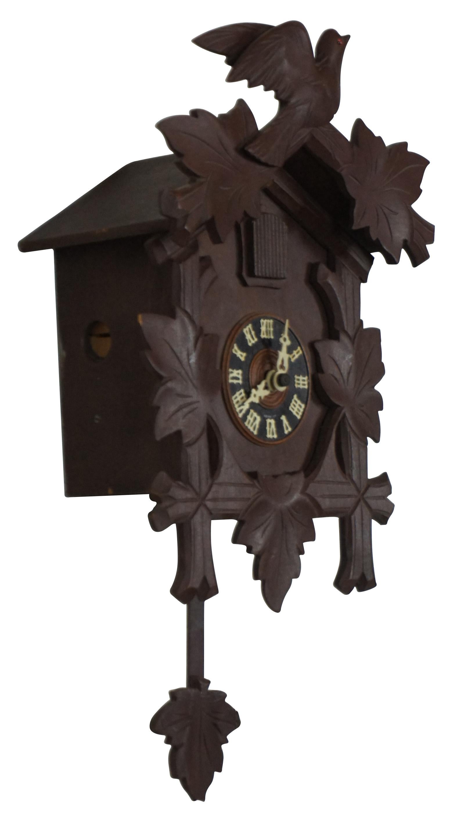 Antique circa 1930’s German Black Forest cuckoo clock decorated with carved branches, leaves and bird with orange glass eye; includes two pine cone weights. G. M. Angem works, marked on back German 605 F.
 