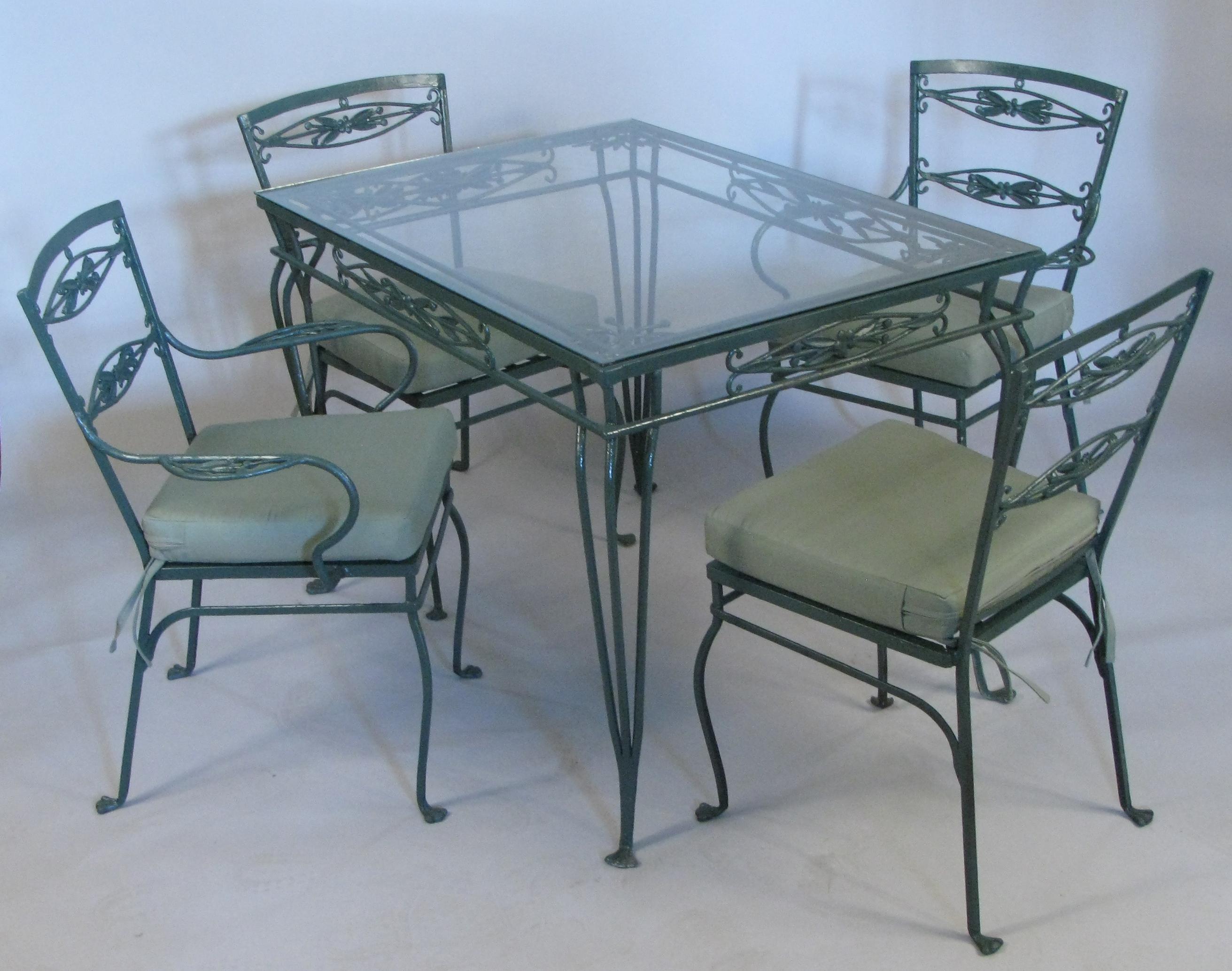 A very charming vintage 1940s dining set with wrought iron frames beautifully detailed with leaves and berries. the set has a pair of armchairs and a pair of armless chairs, as well as the matching glass top dining table. the set has been finished