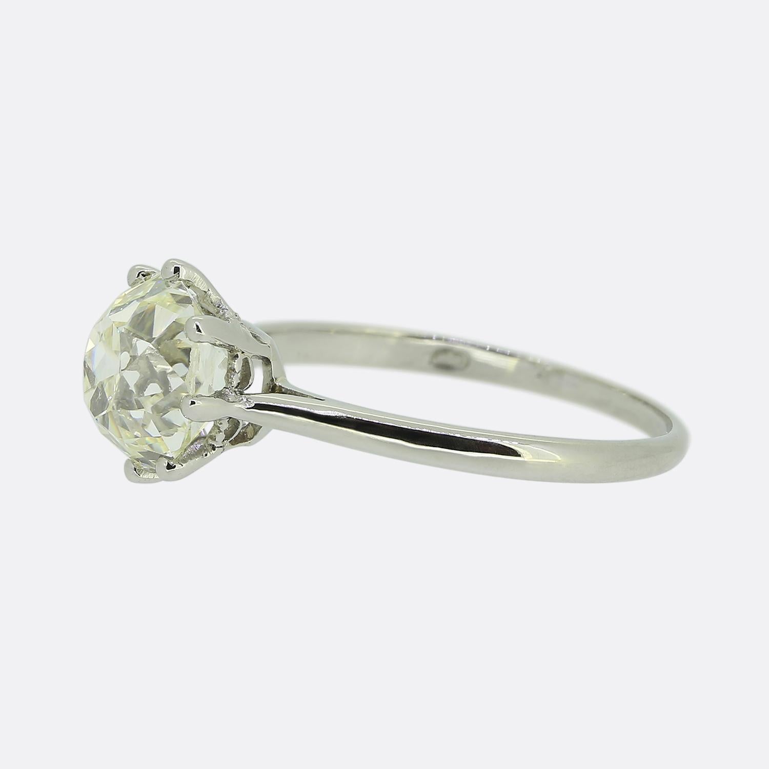 Nous avons ici une captivante bague de fiançailles solitaire. Cette pièce exquise a été réalisée en or blanc 18 ct et présente un seul diamant ancien de taille coussin au centre de la face. Cette pierre centrale se trouve seule et fière dans une
