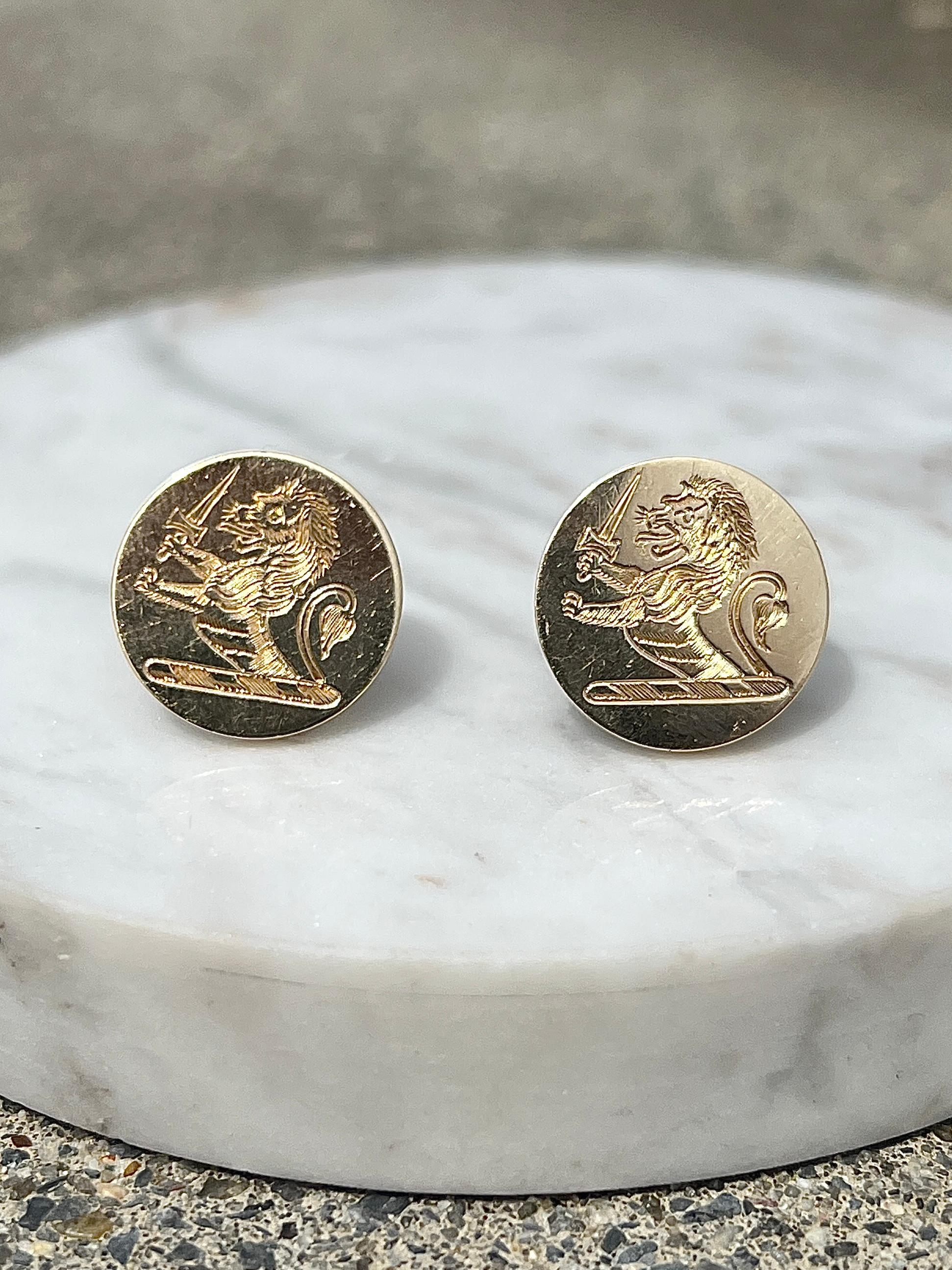 A distinguished pair of antique 1950s earrings crafted in rich 14 karat yellow gold, each featuring a finely hand-engraved heraldic lion set within a polished round disc. The powerful lion motif, rooted in centuries of heraldic tradition, symbolizes