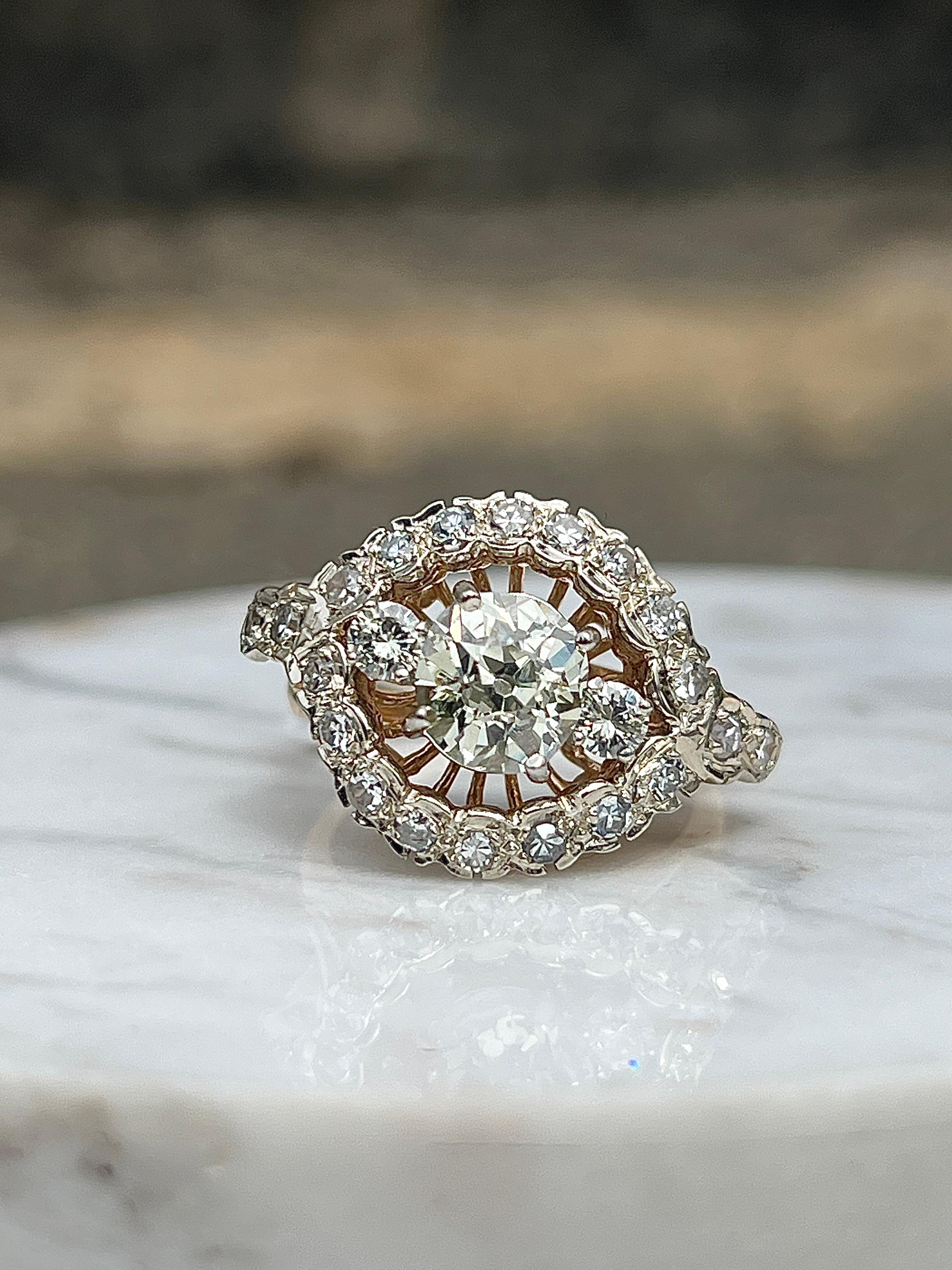 An extraordinary antique ring from the 1970s, showcasing a dramatic and luxurious design in 14 karat yellow and white gold. At its heart lies a captivating antique cushion-cut diamond weighing approximately 1.71 carats, with a soft O/P color and SI2
