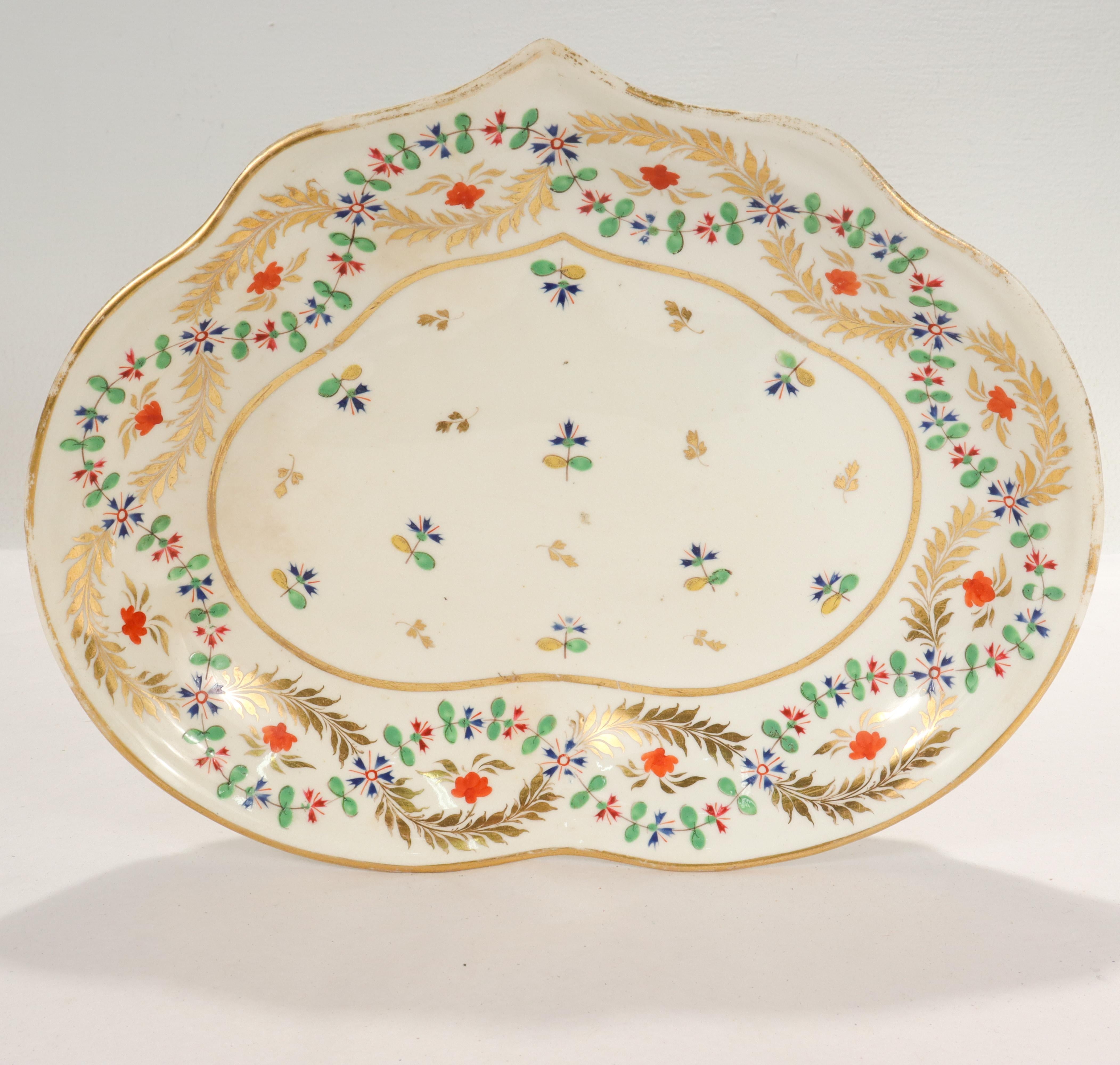 A fine antique 19th century English porcelain shaped dish.

Decorated throughout with a colorfully painted blue cornflower and gilt accents. The rim features intertwining painted flowers and gilt garlands.

Simply a wonderful piece of English