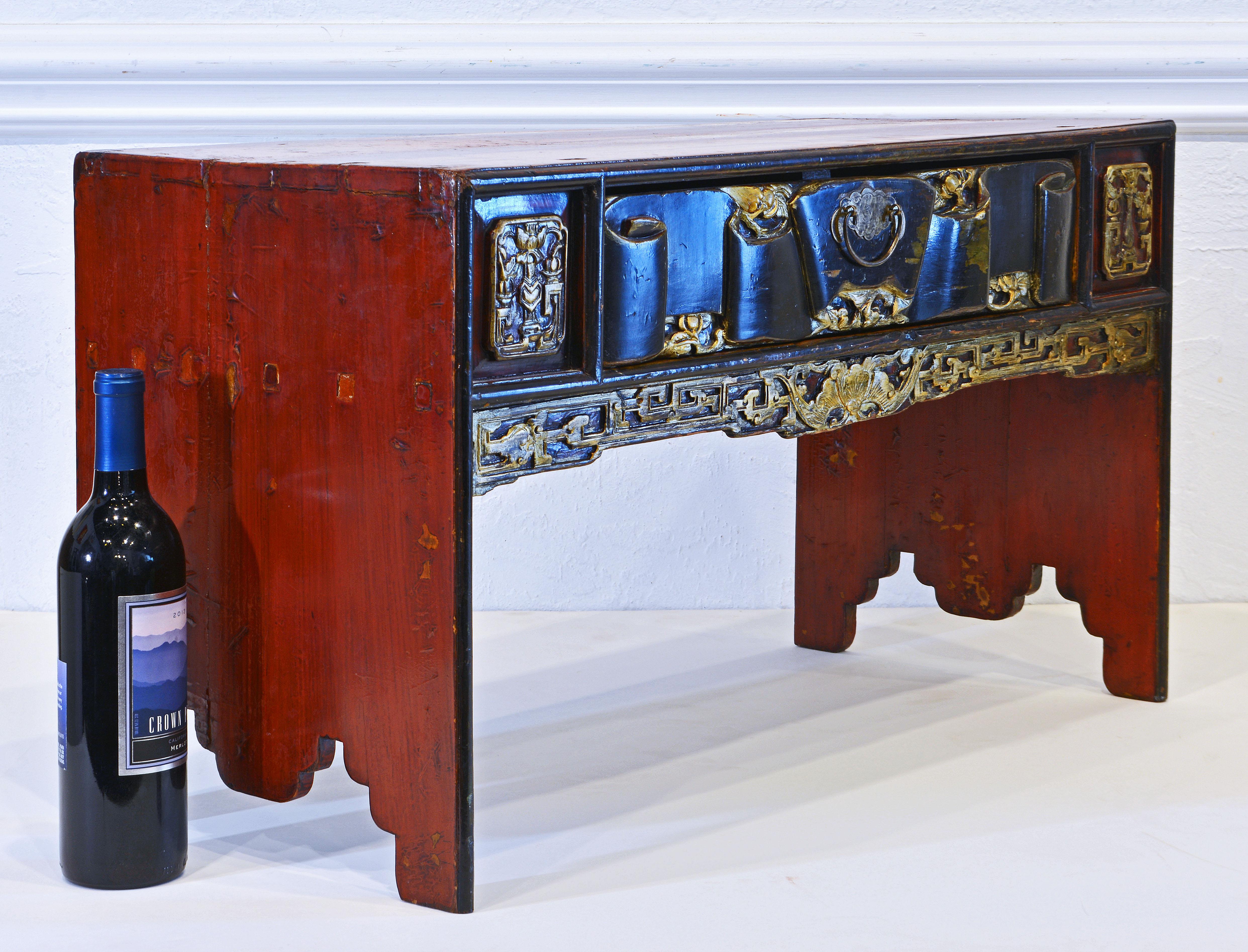 This petite Chinese intricately carved lacquer and gilt altar or praying table dates back to the 19th century. It features a combination of reddish transparent accented by black lacquer and gilt decoration. The exceptional drawer front is carved