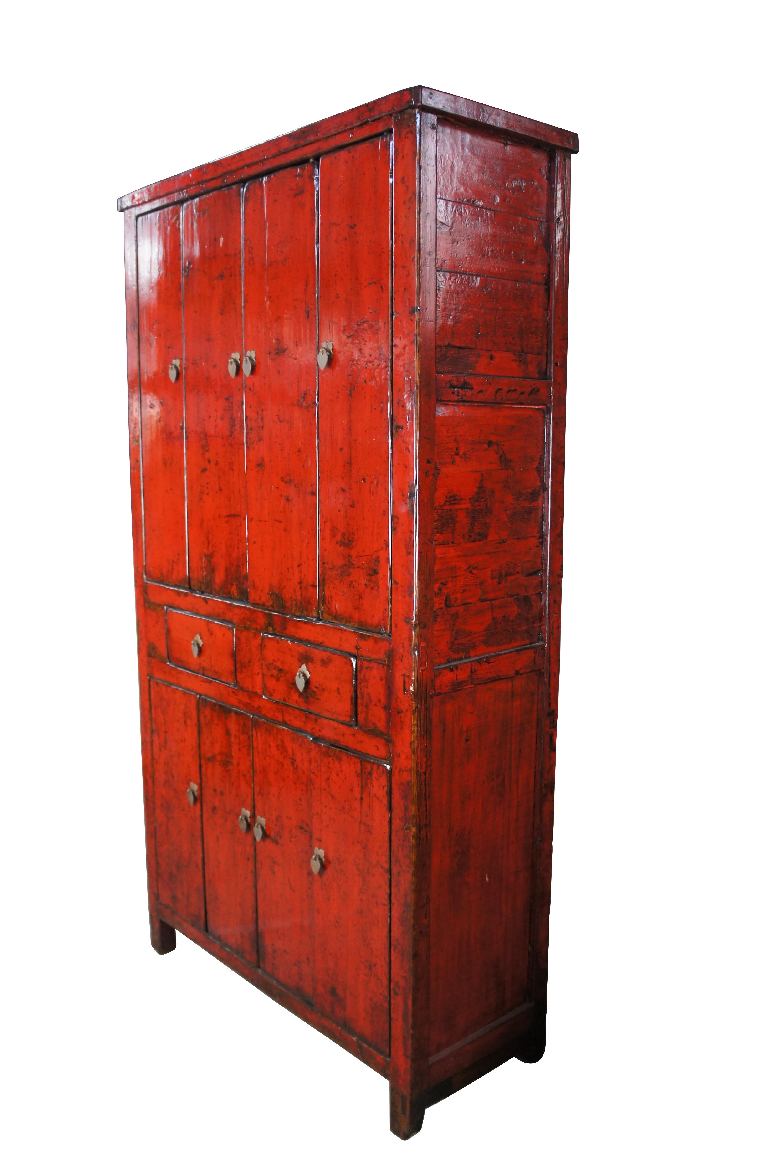 Monumental antique red lacquer Northern Chinese armoire, circa 1870s.  The cabinets large stature sets it apart giving off a very stately vibe.  Made from elm with an exquisite patina.  Features two central drawers and an upper and lower cabinet