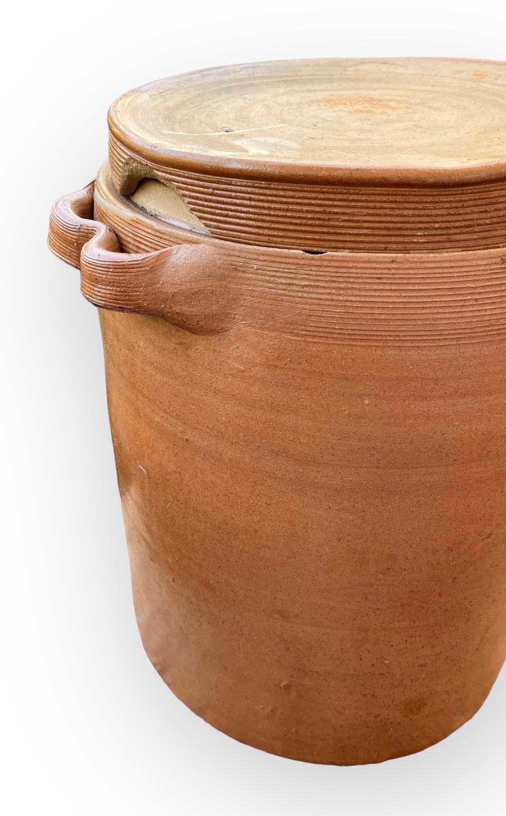 Une merveilleuse grande jarre à confit en poterie française ancienne avec son couvercle d'origine. Cette jarre inhabituelle est d'une taille et d'une forme fabuleuses et possède une belle glaçure et des poignées en ruban. Utilisés à l'origine pour