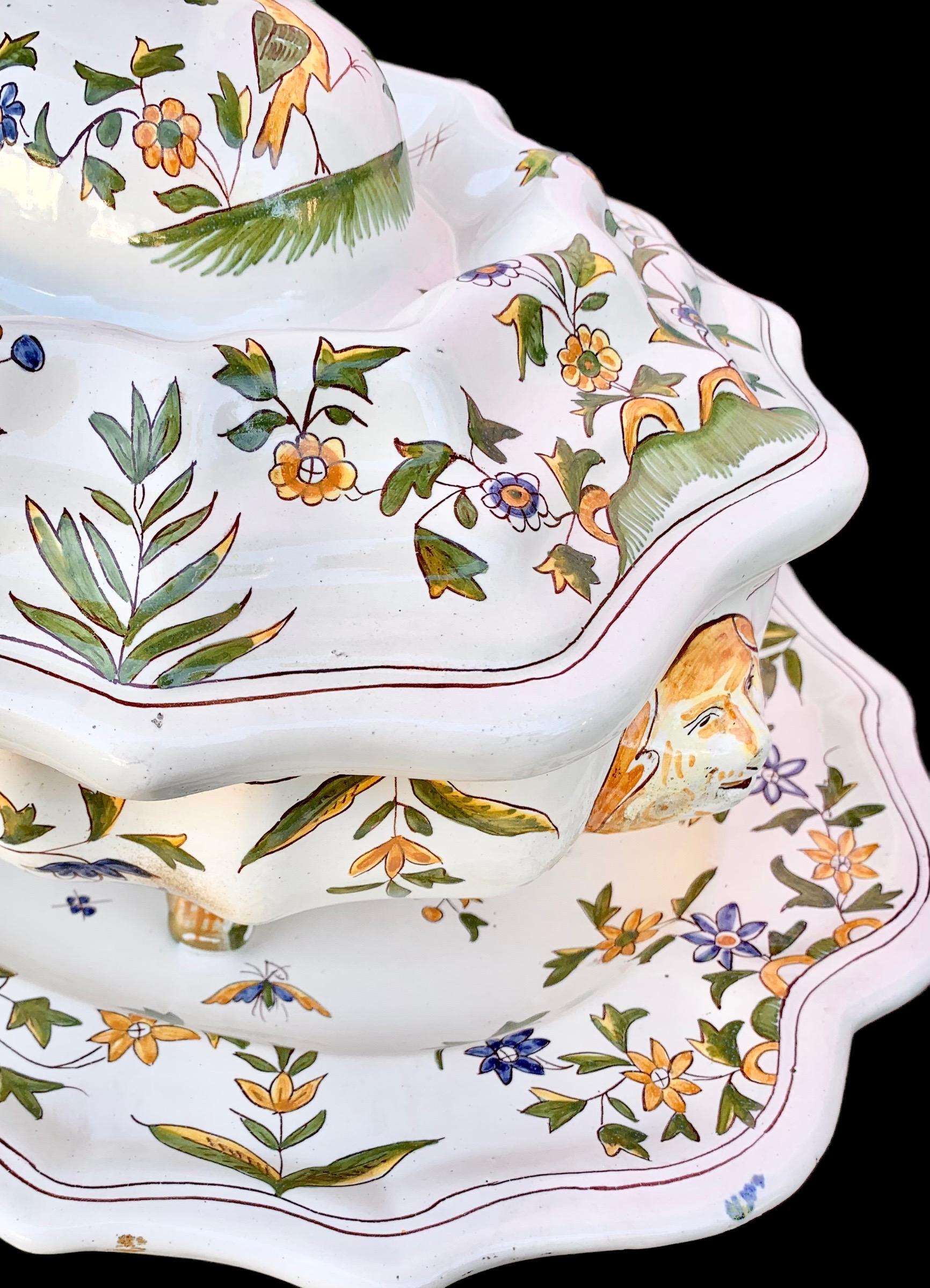Large four quart capacity, antique French hand painted faïence tureen, resting on four lovely painted feet and having its original under platter and the whole decorated with a lovely agrarian theme of birds, flowers/flora, monkeys, and agrarian