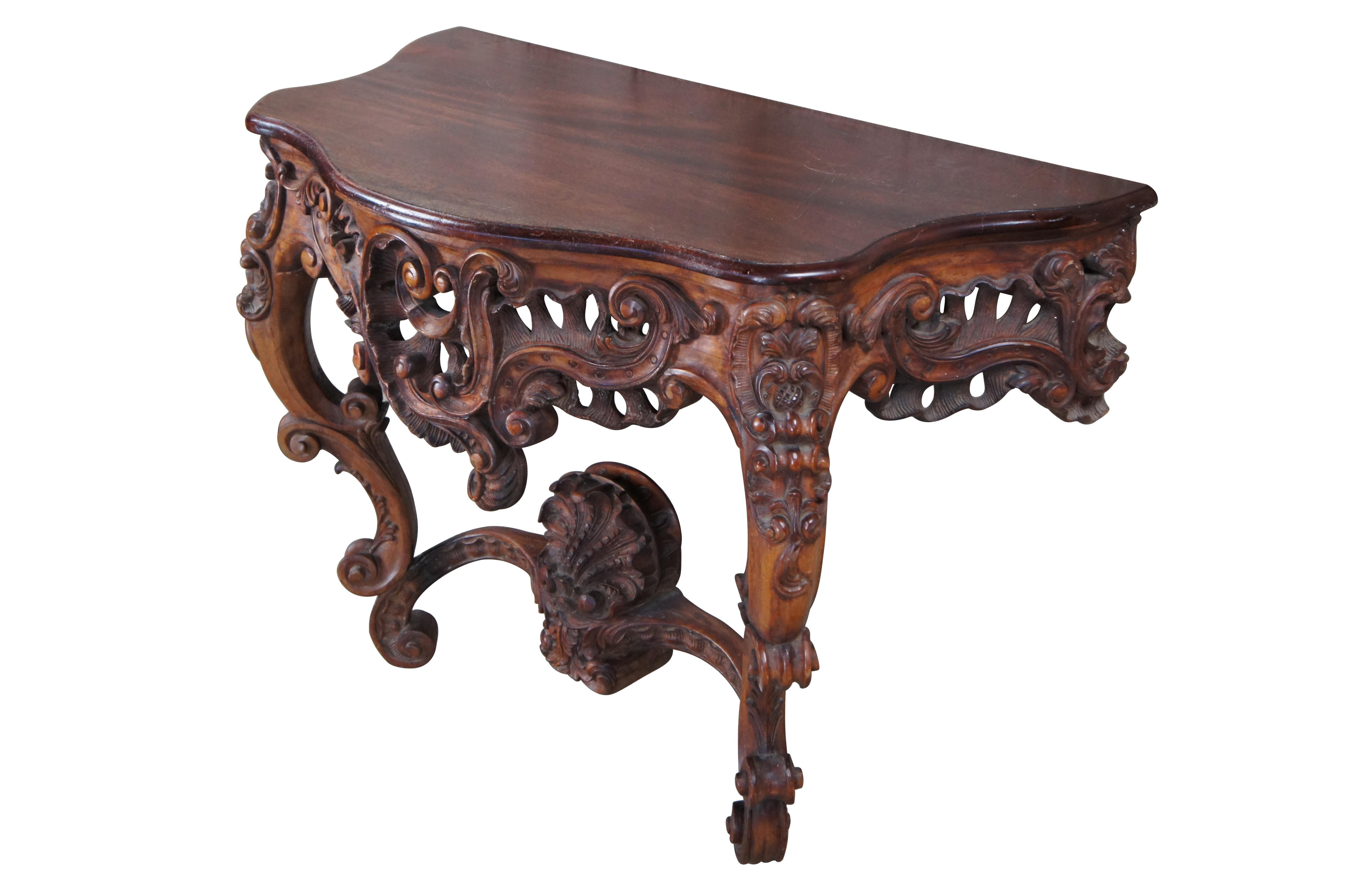 Ancienne console rococo de style Louis XV, vers le milieu du XIXe siècle.  Le cadre en acajou massif est surmonté d'un plateau en forme de tortue serpentine et d'une base méticuleusement sculptée de coquilles Saint-Jacques percées, de feuillages,