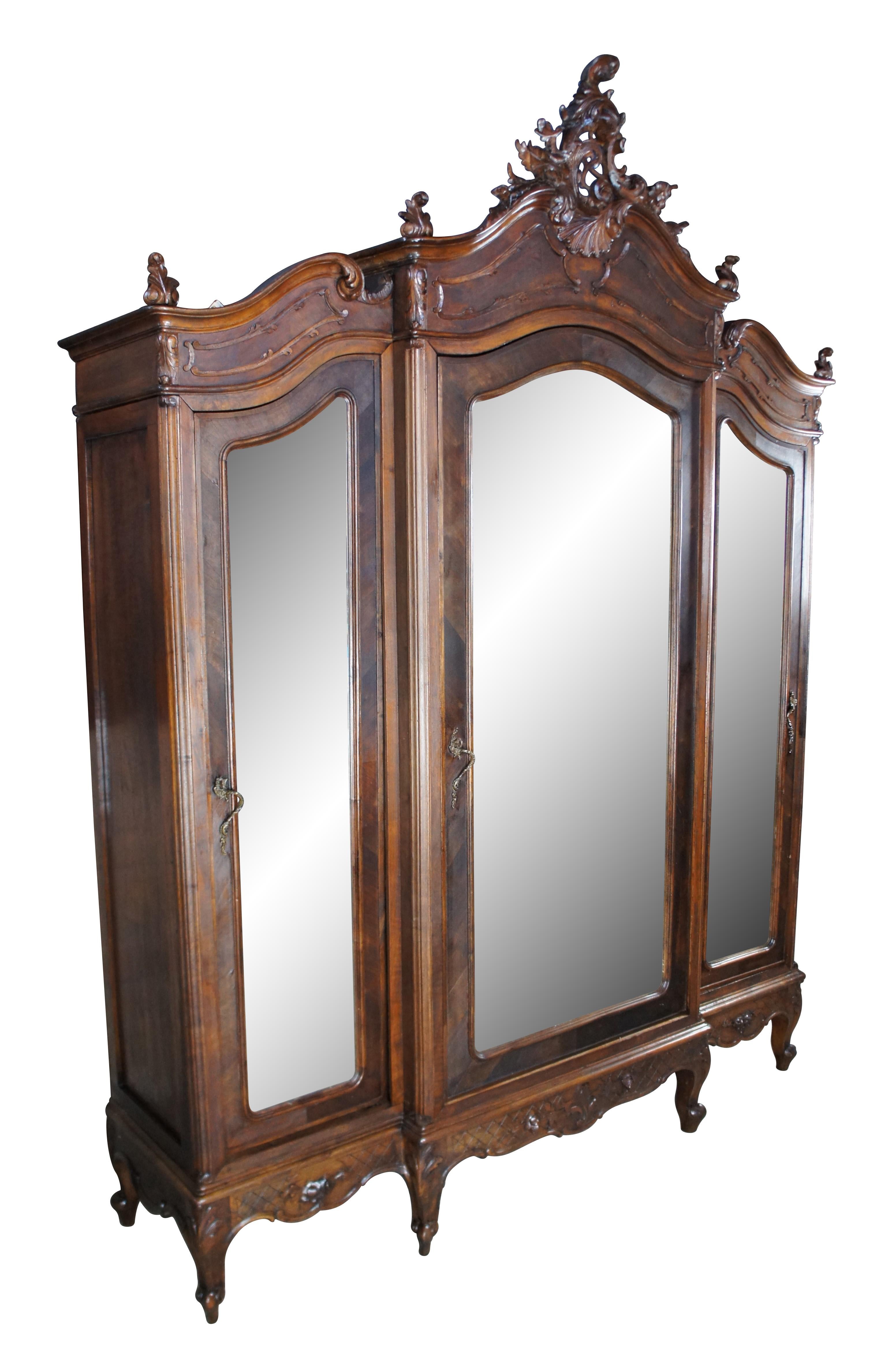 A beautiful antique 19th Century French  Knockdown Armoire / Wardrobe.  Features a walnut frame with three large beveled glass mirrored doors The cabinet opens to a large central area for hanging garments at the center which is flanked by smaller