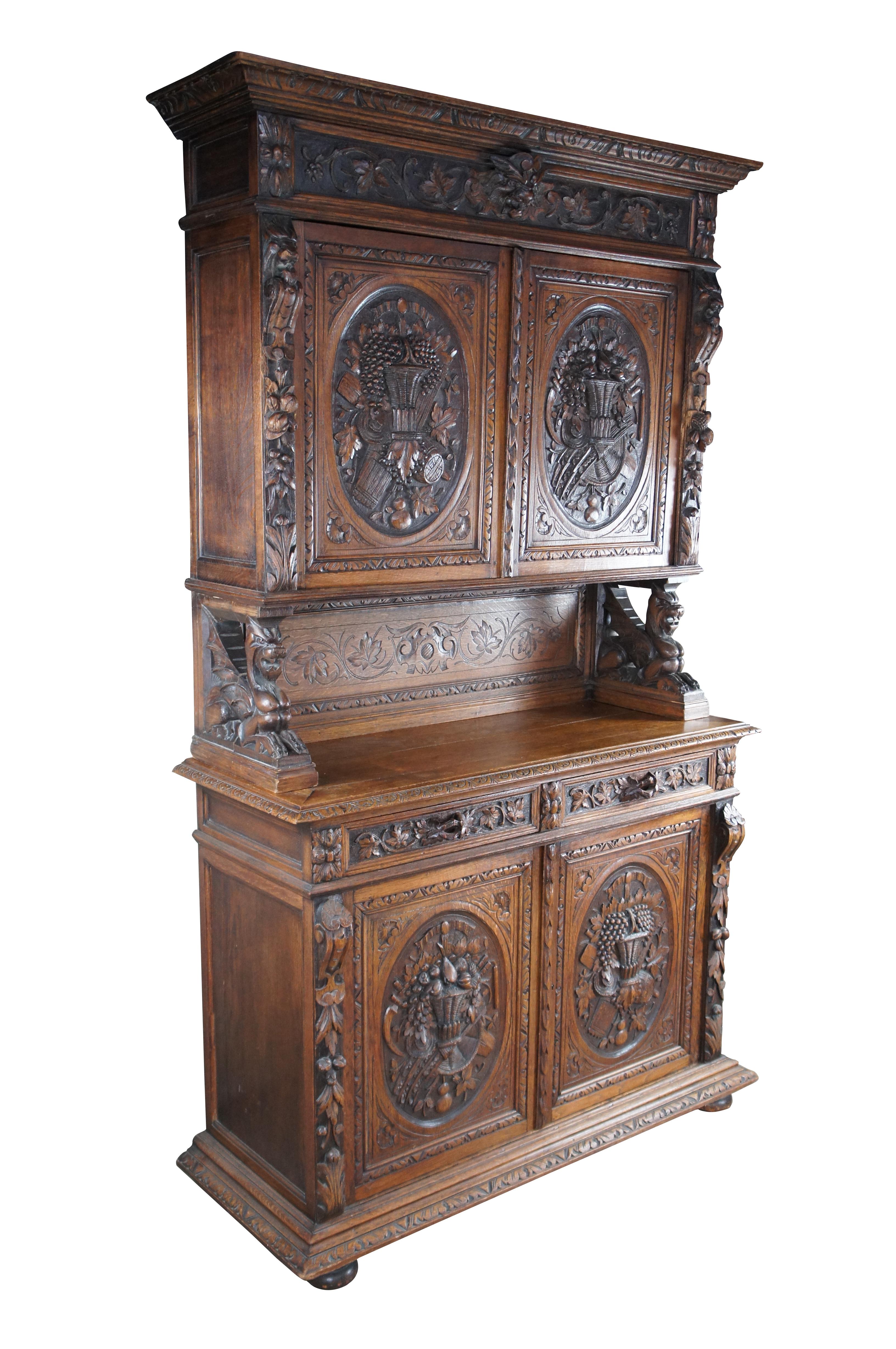 Exceptional Antique 19th Century Renaissance Revival Hunt Cabinet. Hand carved from oak with an upper display portion raised over a figural griffon carved backsplash. Features low relief carved doors with neoclassical motifs showcasing a basket of