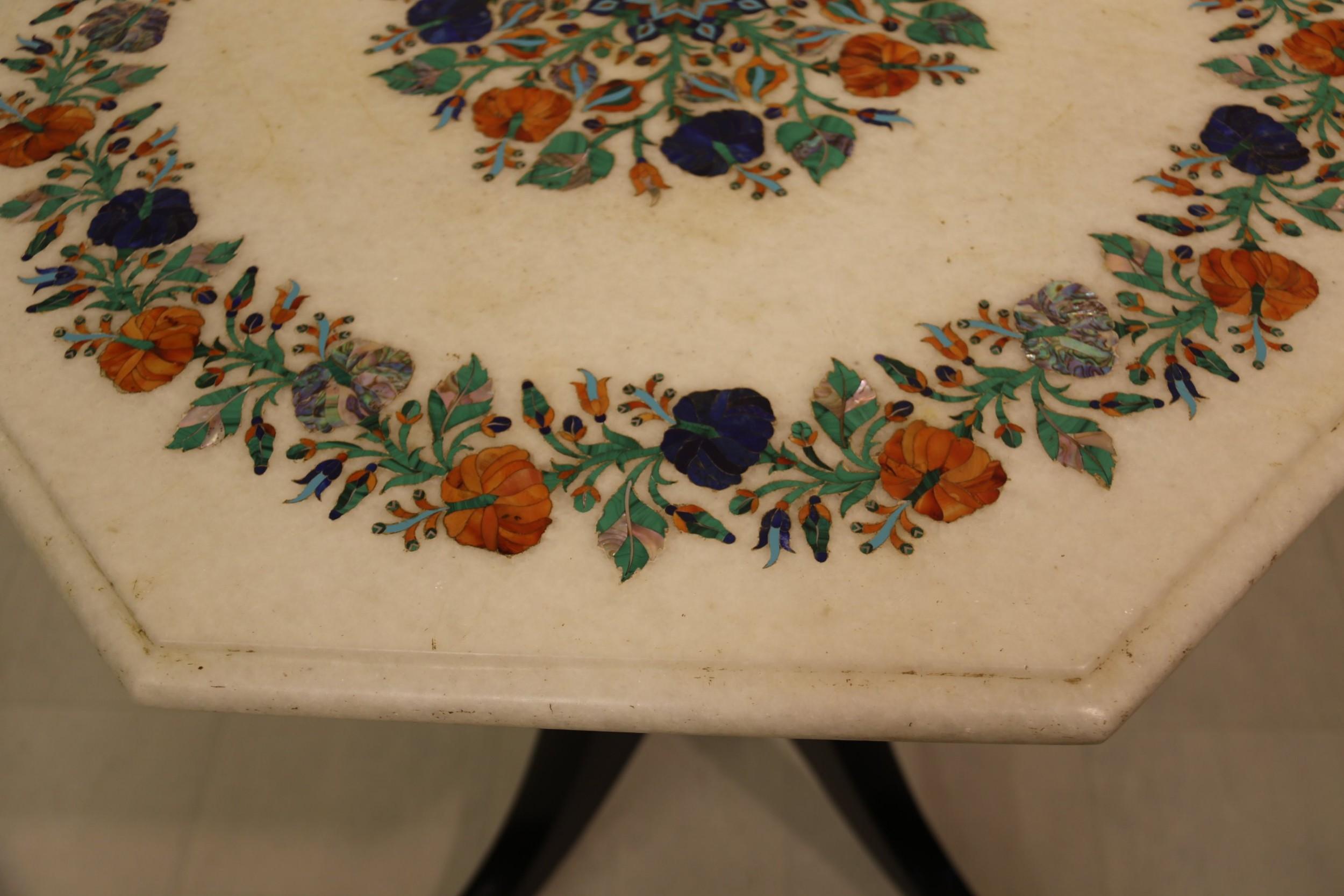 This high quality decorative piece is made up of a very fine Indian white marble octagonal tabletop decorated with inlaid semi-precious cut stones forming a floral design with malachite, lapis, agate, turquoise, and mother of pearl.
The tabletop is