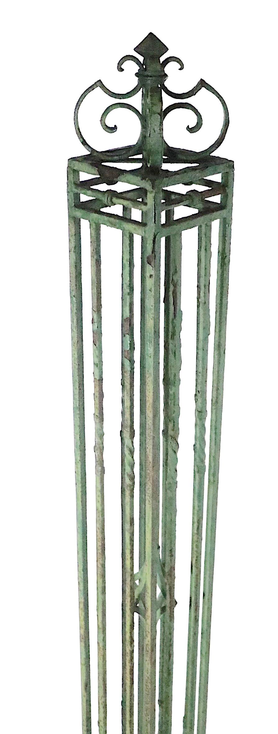 Impressive architectural iron fence post in original old paint finish, constructed of cast and wrought iron. The post features a exterior cage of repeating vertical shafts, on a stepped base, with a decorative scrollwork top. The finish shows