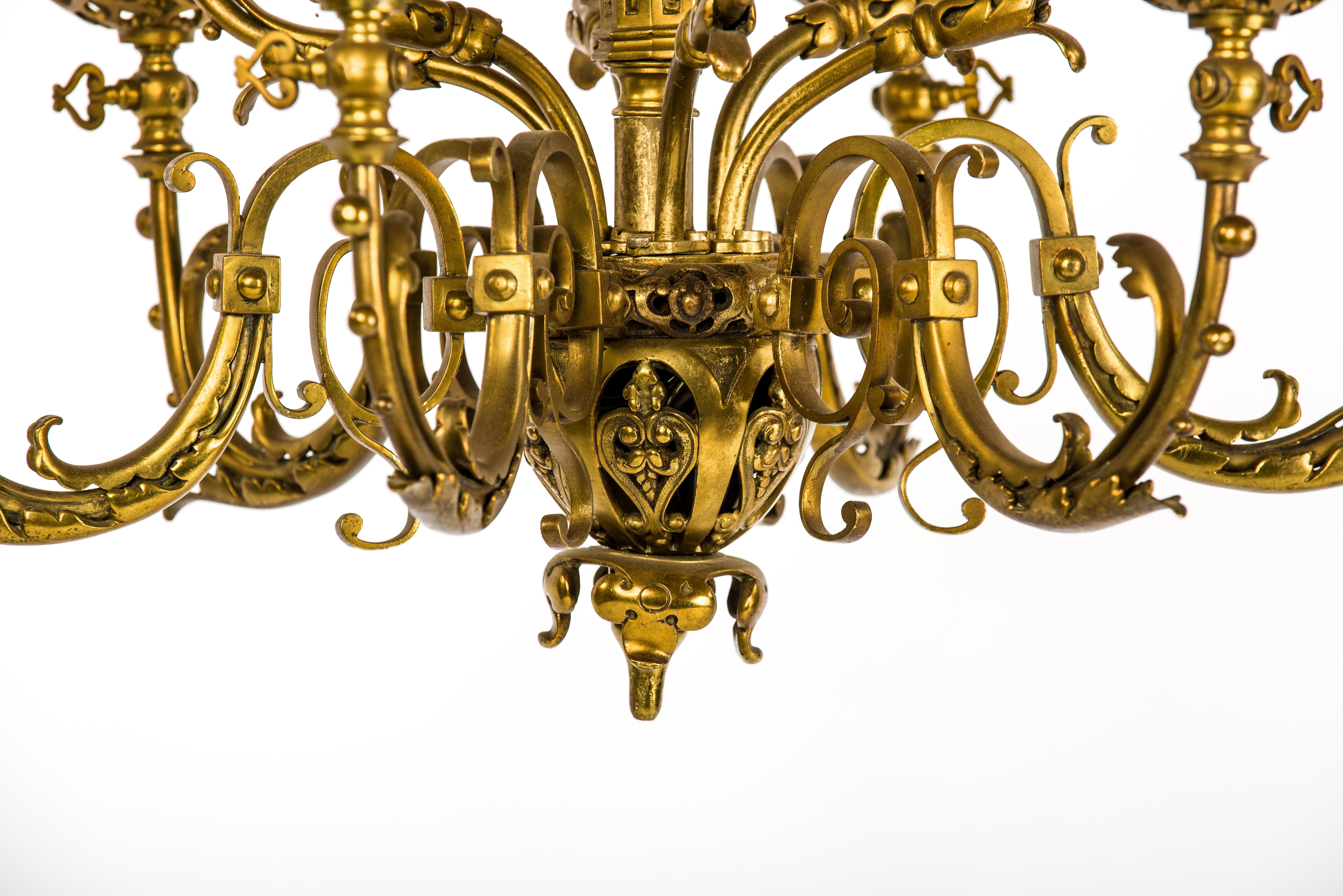 This impressive two-tier chandelier was made in France in the late 19th century. The piece is completely made in brass and it is heavily decorated with many classic Renaissance ornaments such as scrolls and acanthus leaves. The brass ornaments were