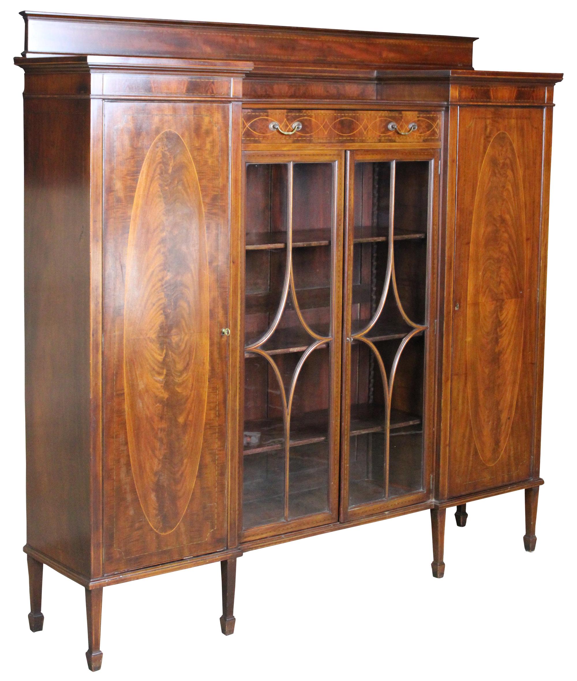 Monumental early 19th century Sheraton library bookcase. Features a central curio cabinet and upper drawer flanked by outer bookcases. Made from crotch (flamed) mahogany with beautifully burled doors, satinwood inlay, diamond pattern fretwork and