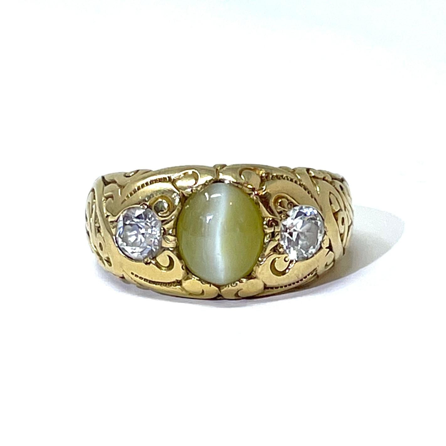 A handsome Gentleman's ring containing a Cat's eye chrysoberyl weighing approximately 2.40 carats flanked by two old mine cut diamonds weighing approximately 0.80 carats total weight set in 14K engraved gold. Circa 1890-1910.

Engraved inside: Oct.