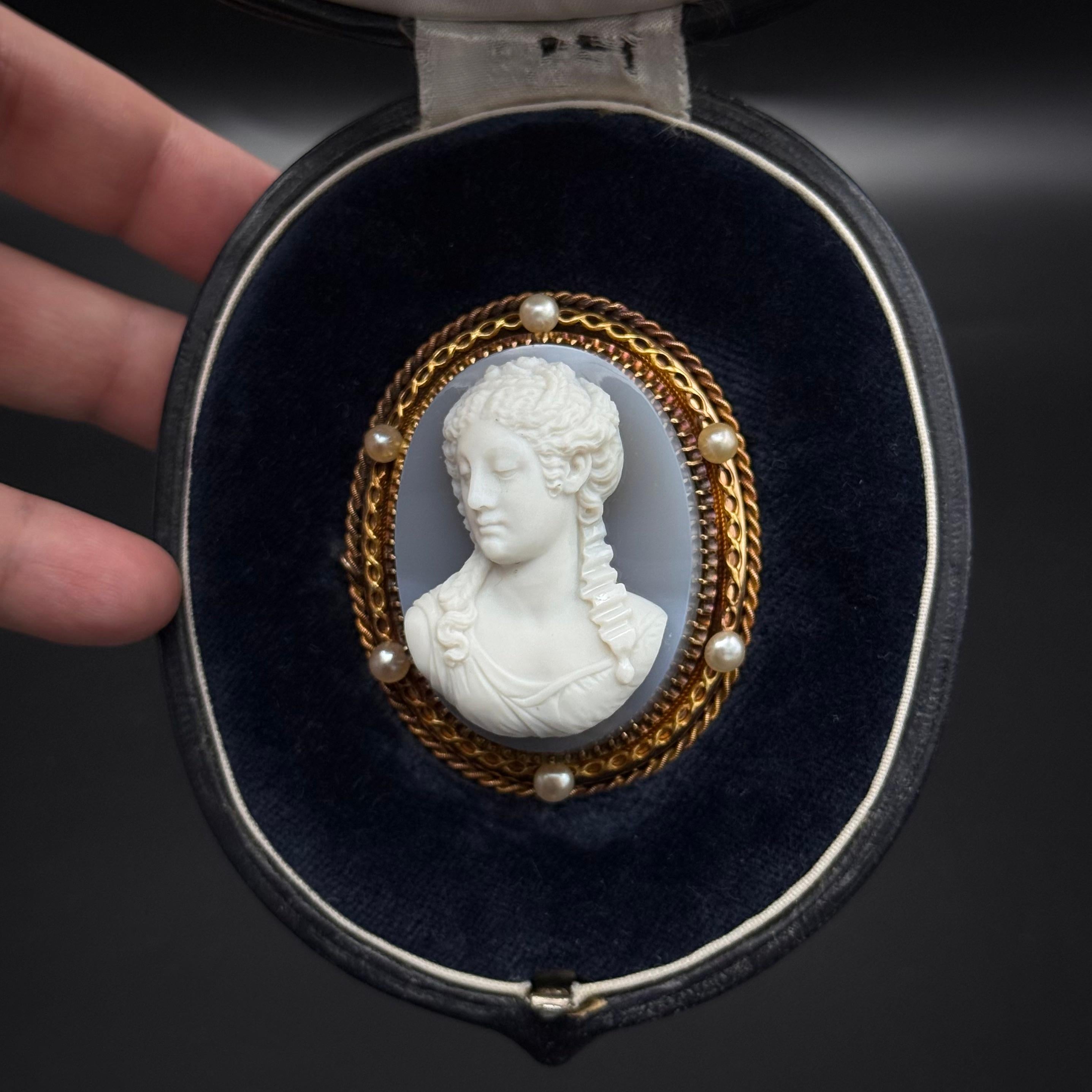 19th Century Agate Cameo Brooch with Natural Pearls in Yellow and Rose Gold, France. A finely crafted 19th-century cameo brooch featuring a female bust delicately carved in white-over-gray banded agate chalcedony. The cameo is claw-set within a