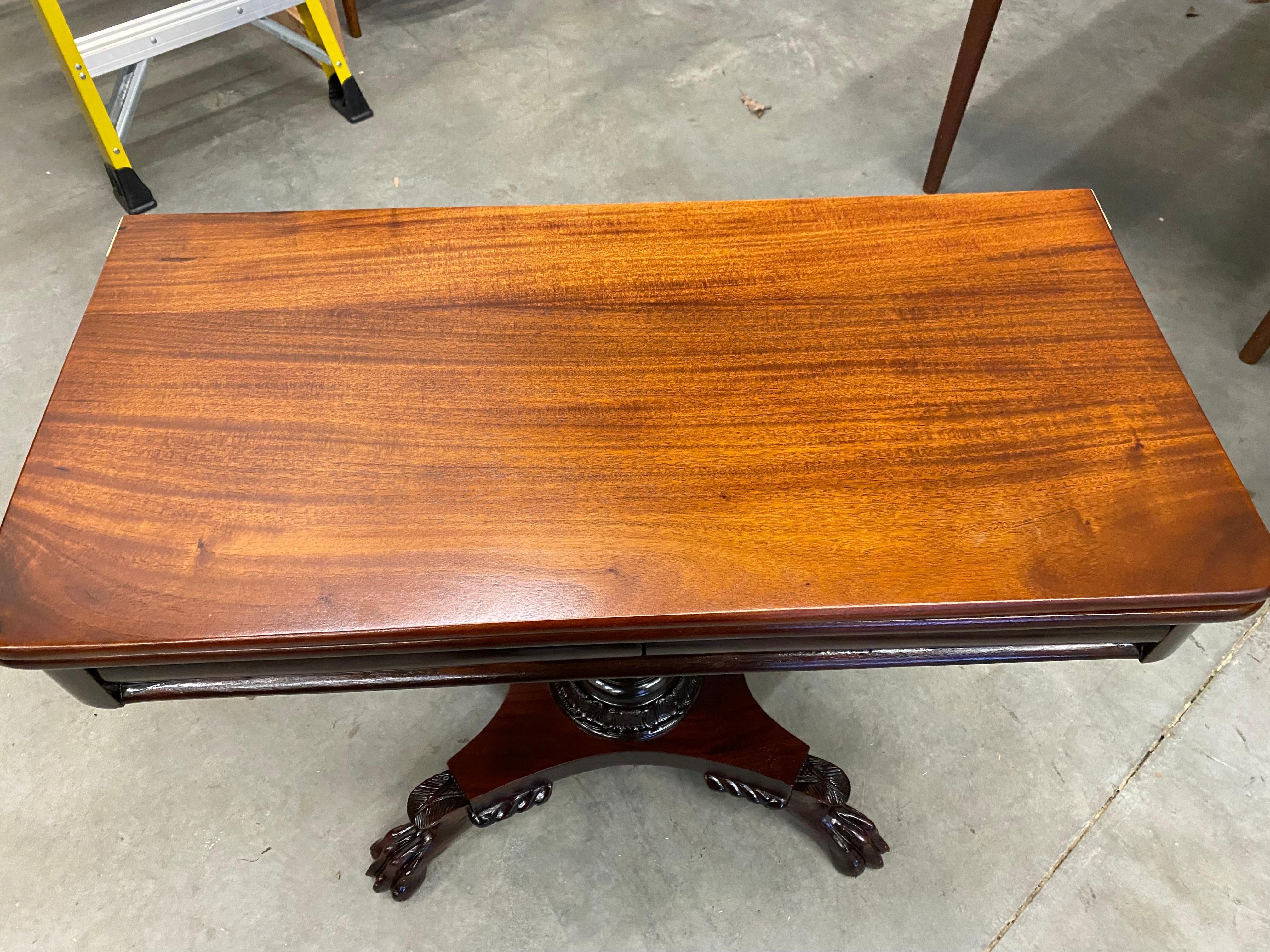 American Classical mahogany card table, second quarter 19th century, having a single hinged fold top with acanthus carved support ending in paw feet. Solid hand carved mahogany with the finish restored. 

Dimensions: height closed 28 1/4in; width