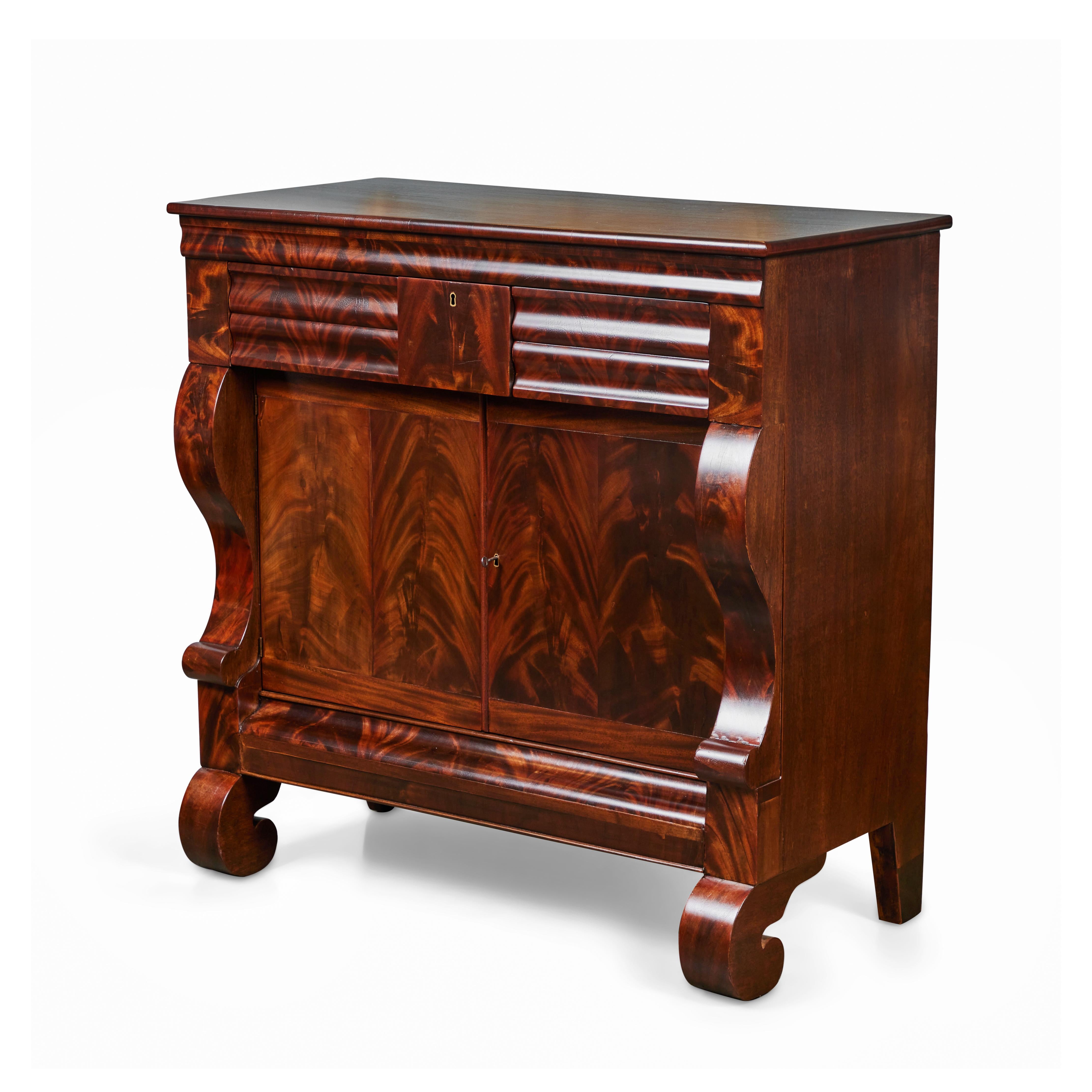 This stately ​antique 19th Century American Empire Flame​ ​Mahogany cabinet has 3 drawers​ and a two hinged door large cabinet for ample storage​. The middle drawer has a lock but there is no key. The doors are made from exceptional book-matched