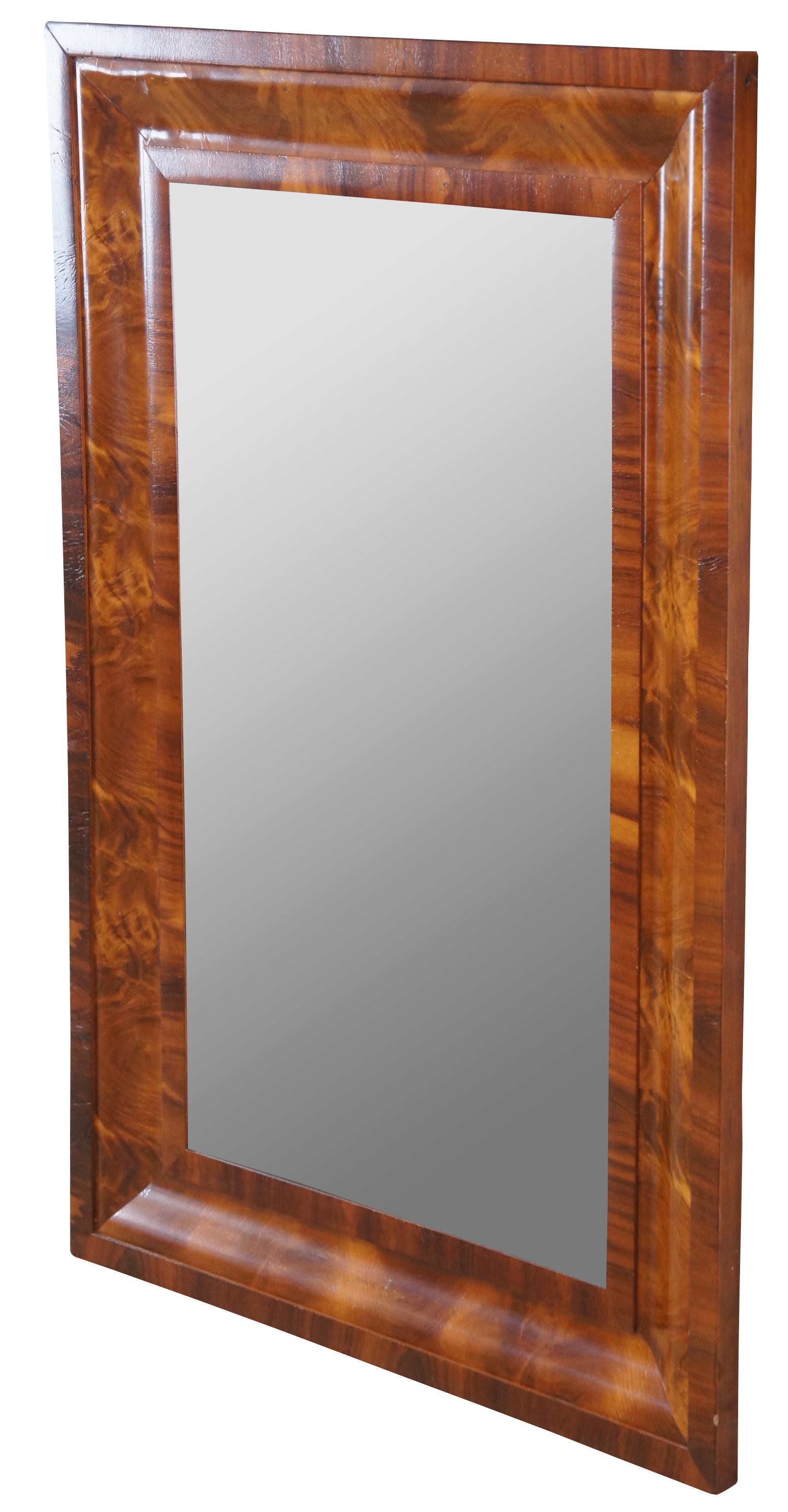 An American Empire mirror, circa 1860s. Features rectangular plate set within an ogee flame mahogany veneered frame. The mirror can be hung vertically or horizontally. Measure: 38