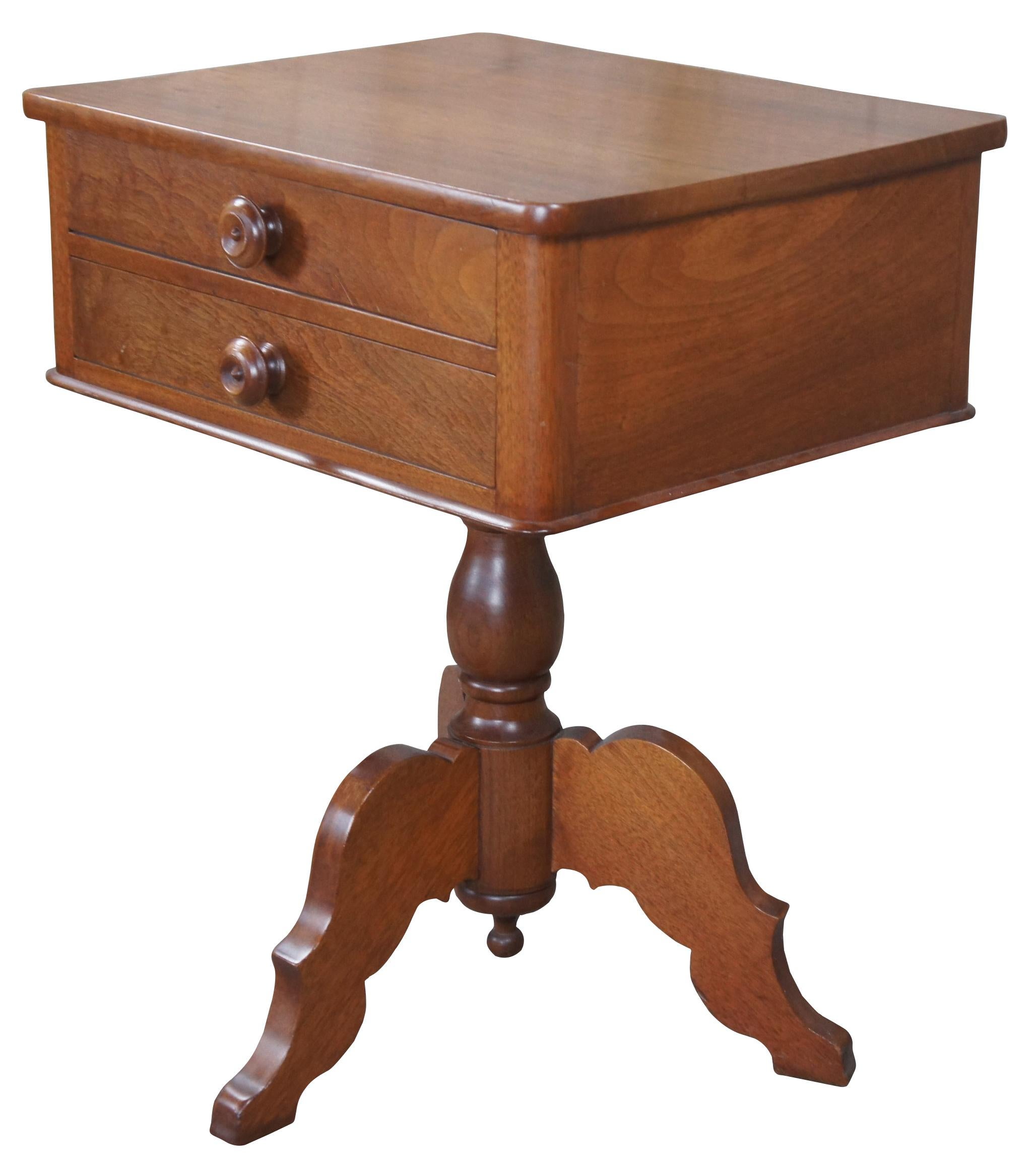 Antique American Empire parlor sewing table. Made of walnut featuring rectangular form with two hand dovetailed drawers over a turned pedestal tripod base.
Measures: 29