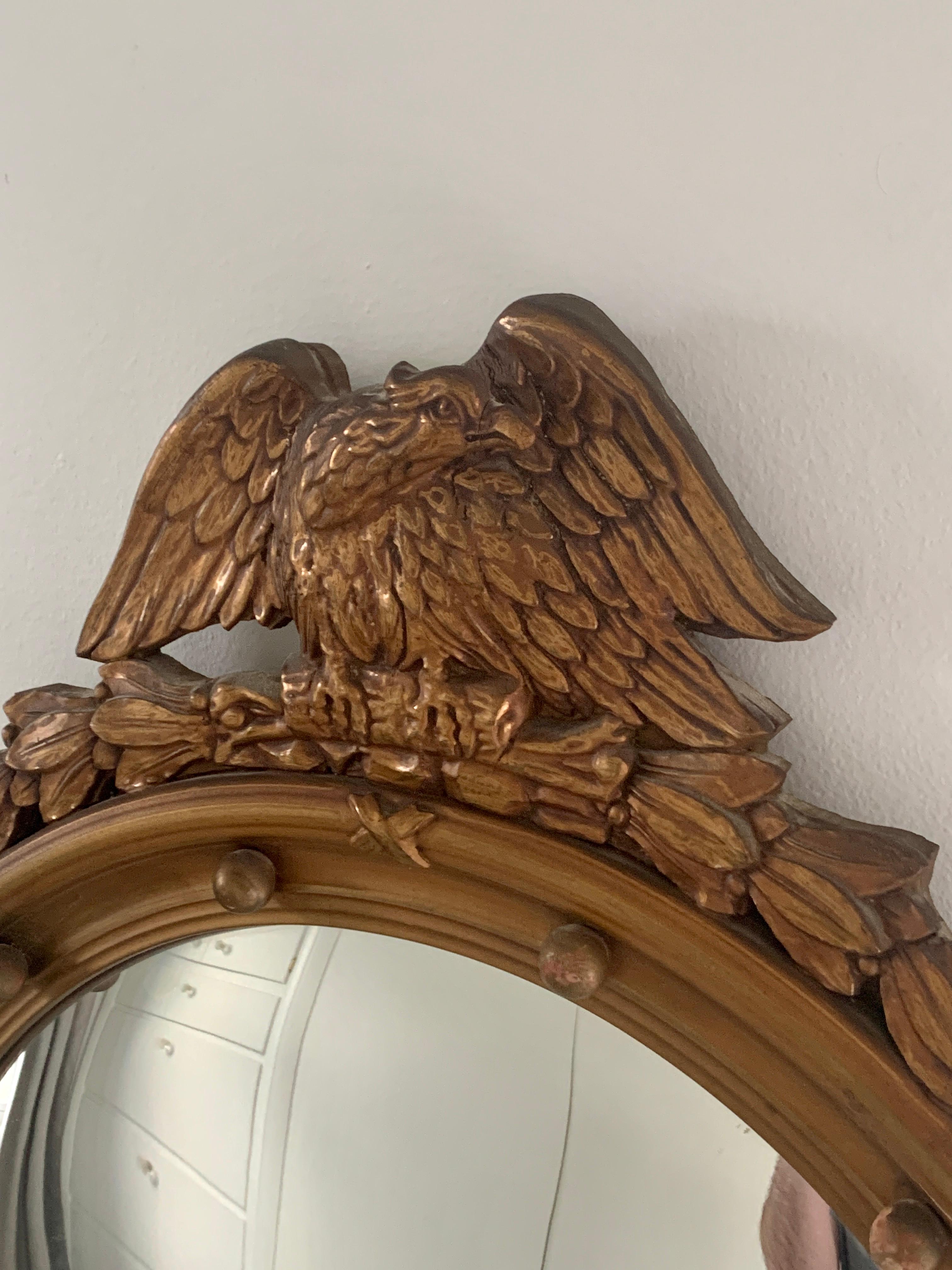 A gorgeous Federal or Regency style convex bullseye wall mirror featuring a carved eagle with open wings standing on olive branches and 13 small spheres representing the original 13 colonies around the inside perimeter.

USA, Late 19th