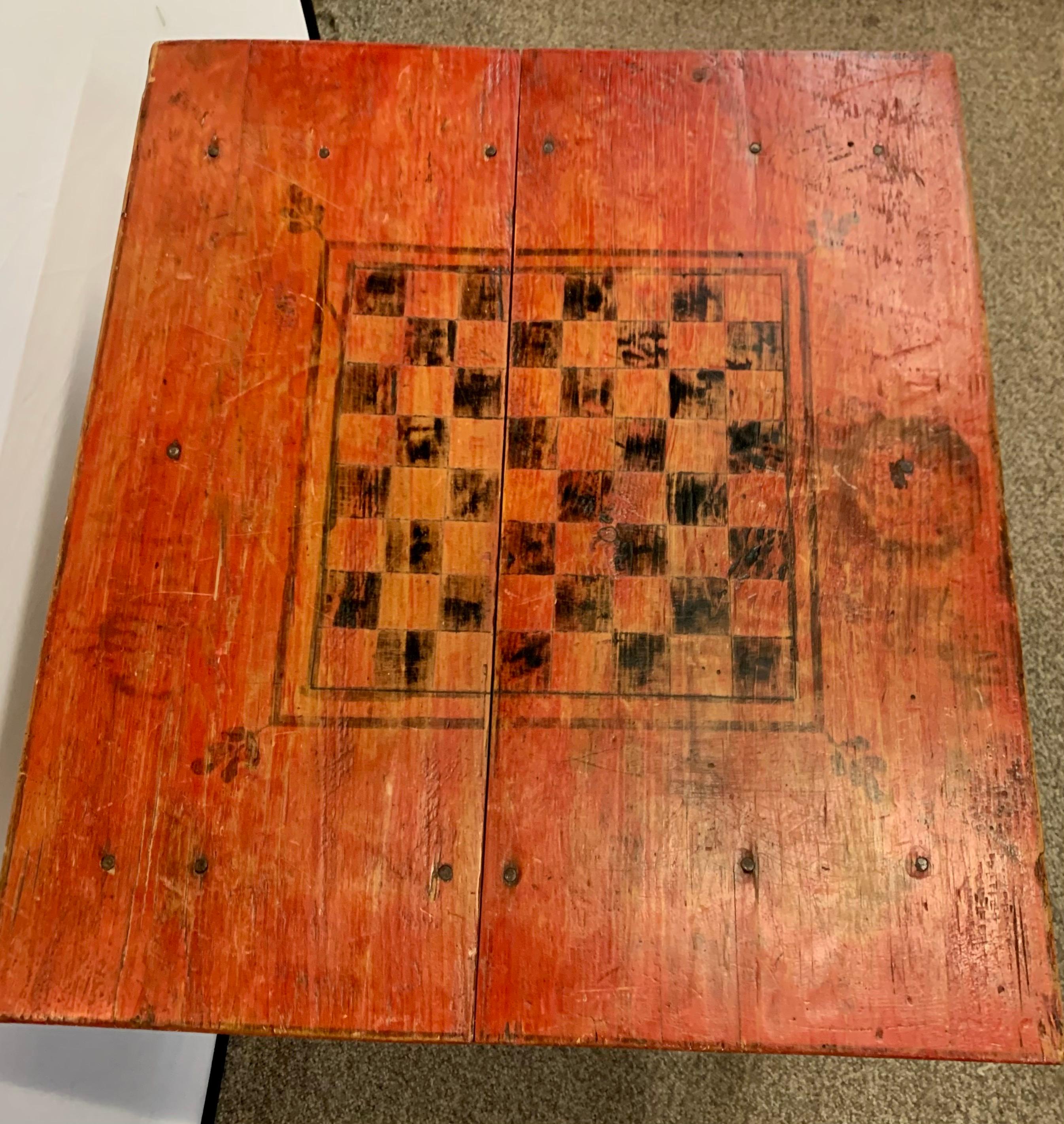 Handmade antique American primitive red game table with black checkerboard pattern. Item features a square top and solid wood construction. Great distressed patina only acquired through its age and use.