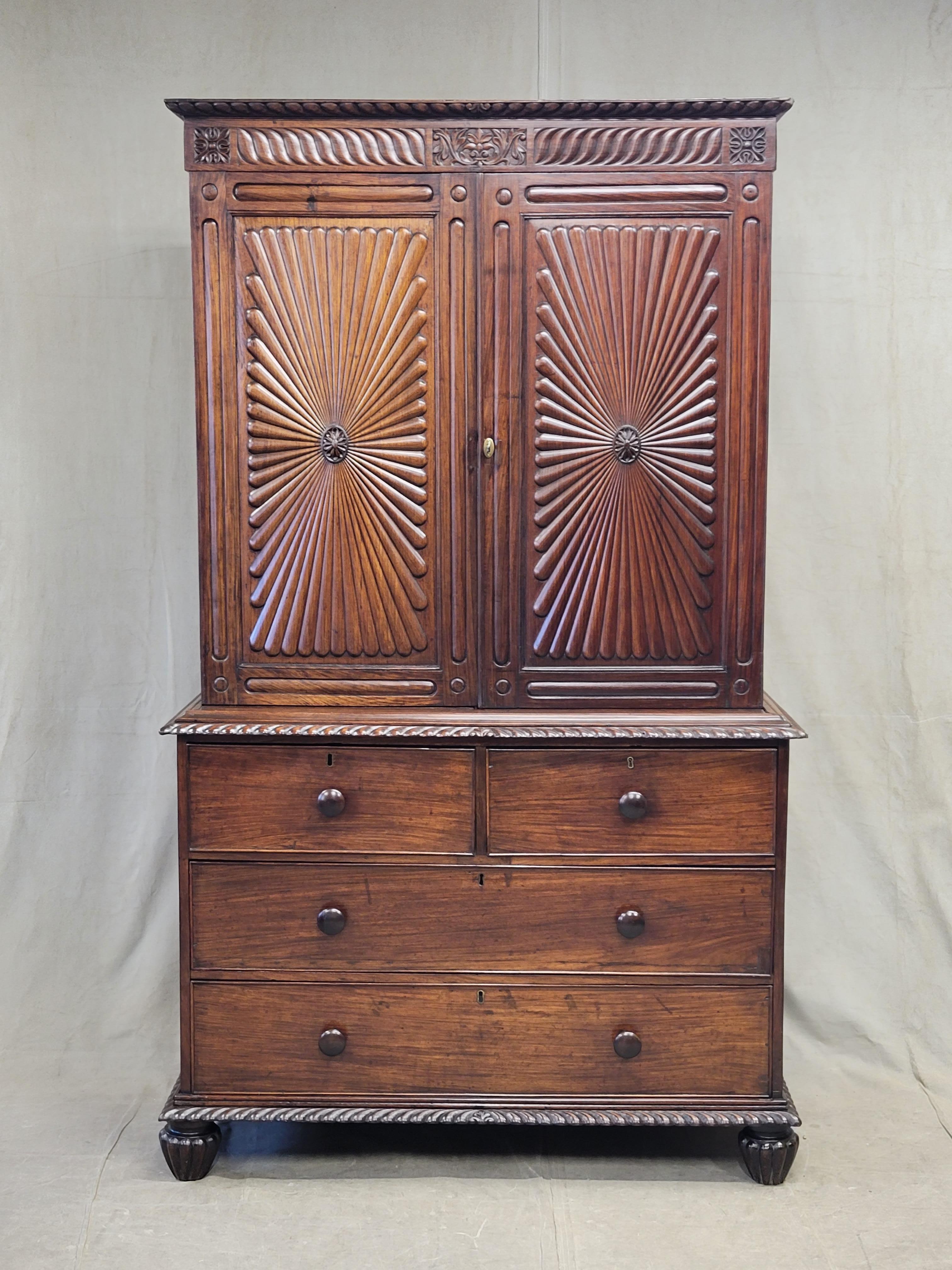 An absolutely stunning antique mid to late 19th century Anglo-Indian British colonial rosewood linen press cabinet. The rosewood just glows! A carved starburst pattern adorns the doors and a gorgeous carved gadrooned pattern is on the top, middle