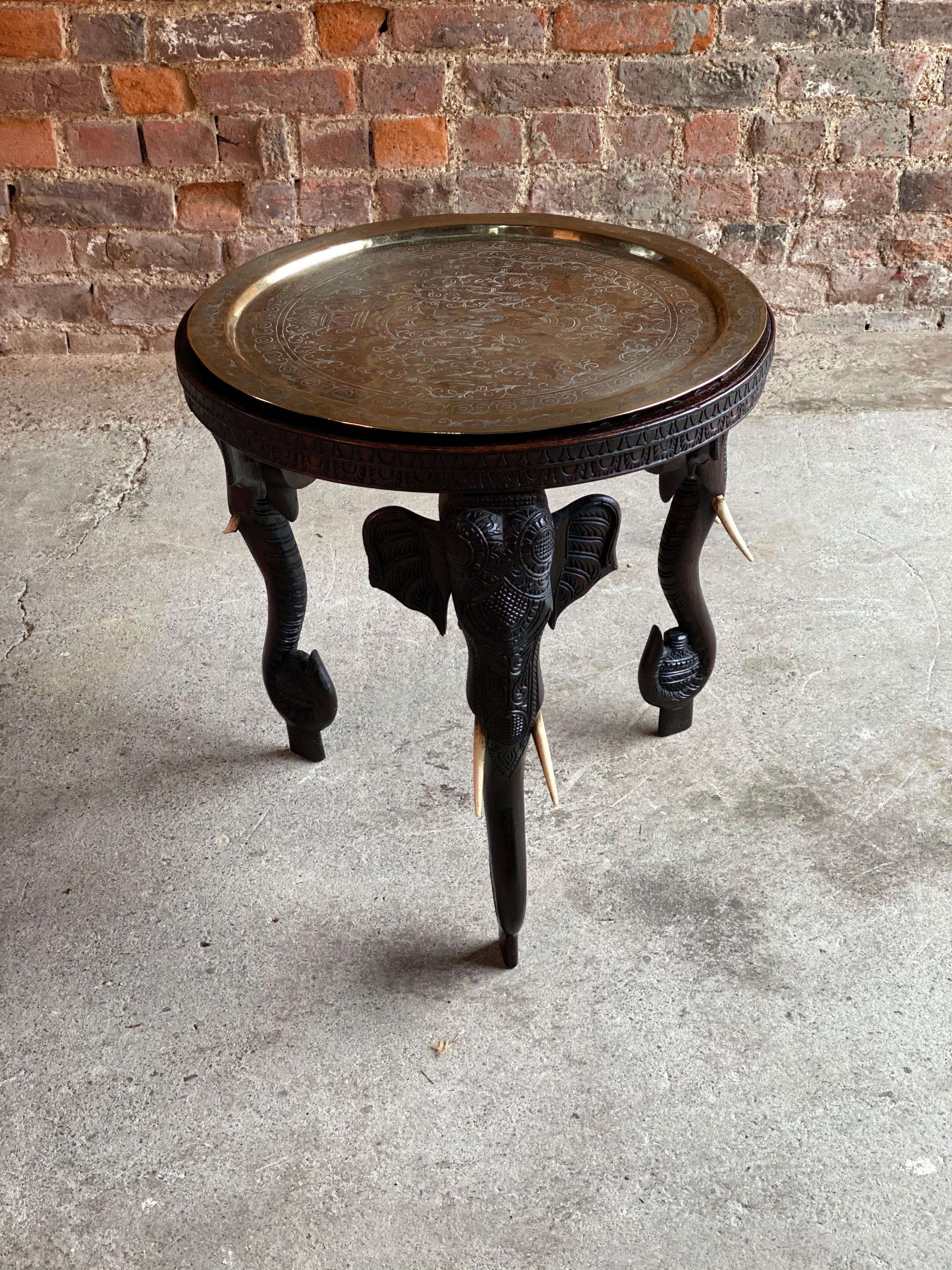 Antique 19th century Anglo-Indian Elephant side table circa 1890, the heavily carved top comes with a circular embossed and engraved brass tray, the table with three elephant legs, the profusely carved top with a central Indian Goddess flanked by