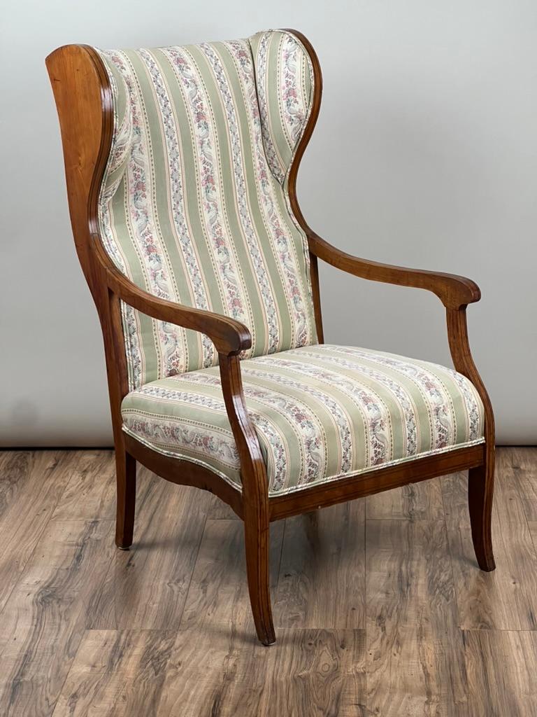 This elegant wing back chair reflects the restrained beauty of the Biedermeier period, likely crafted in Germany or Austria in the mid to late 19th century. Made of warm, honey-toned fruitwood, the frame is gently curved and well-proportioned, with