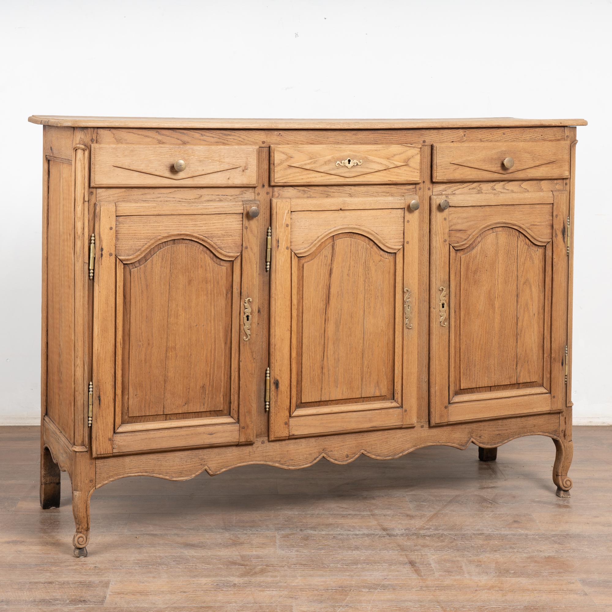 Dieses Sideboard aus französischer Eiche unterscheidet sich von anderen durch die gewölbten Türen, die geschwungene Schürze und die Rautenstruktur der Schubladen.
Die gebleichte Oberfläche verleiht ihm ein frisches und einladendes Aussehen für das