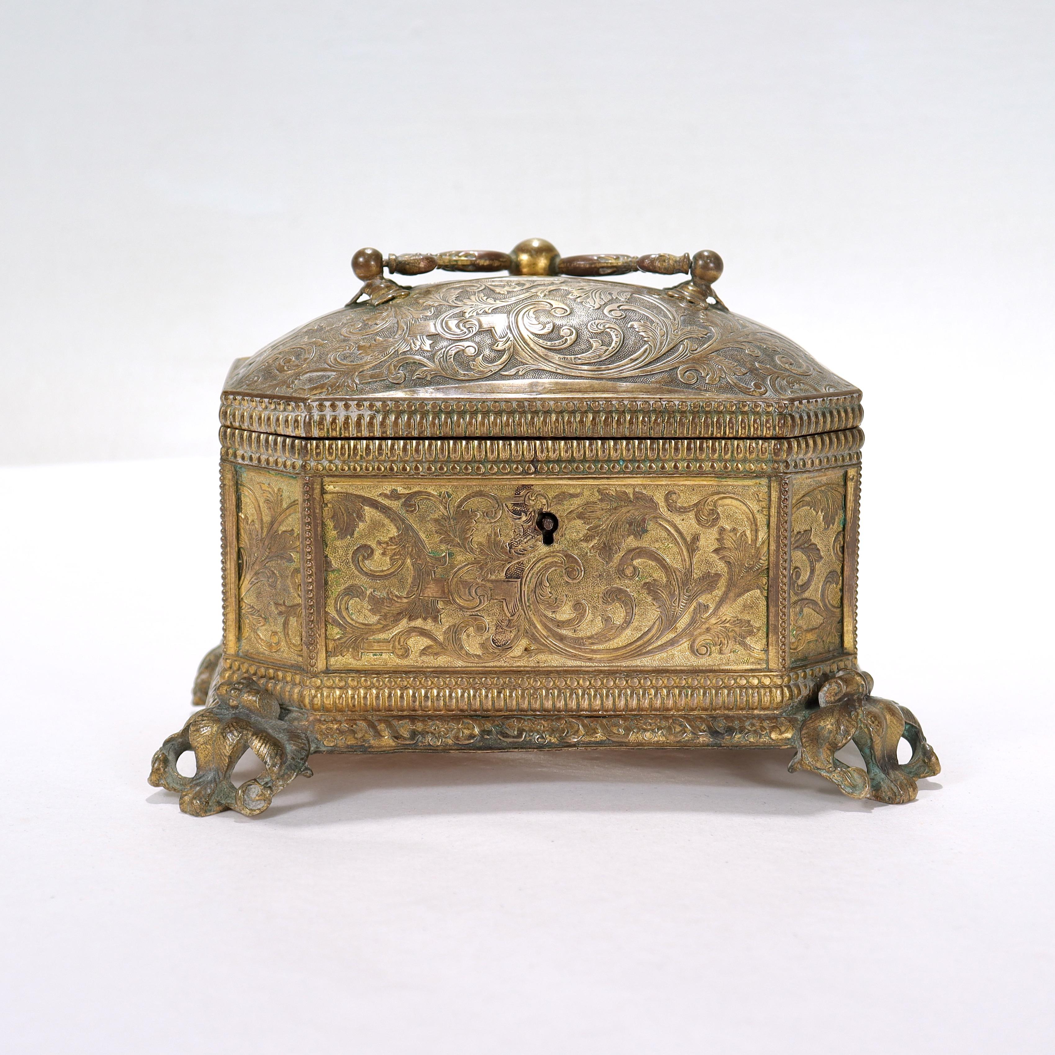 A fine antique 19th Century brass casket or table box.

In the Renaissance Revival style.

With embossed brass sheet side panels, a domed lid, bail handle, and scroll & leaf work feet. 

Retains some of the original gilding.

Decorated throughout
