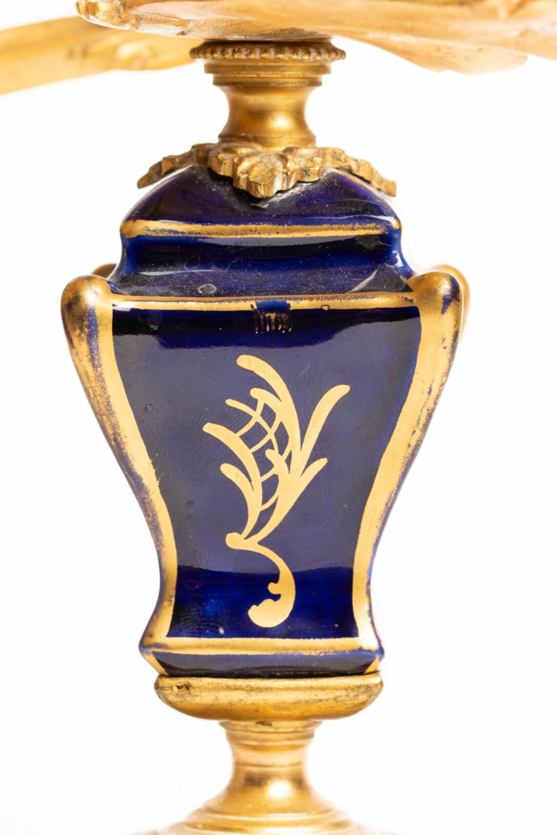 Très beau candélabre français à deux cônes en bronze doré et porcelaine, vers le 19e siècle. 

Le chandelier est décoré de porcelaine bleu cobalt avec une marque dorée sur trois côtés et un petit Chérubin délicatement peint à la main dans les nuages