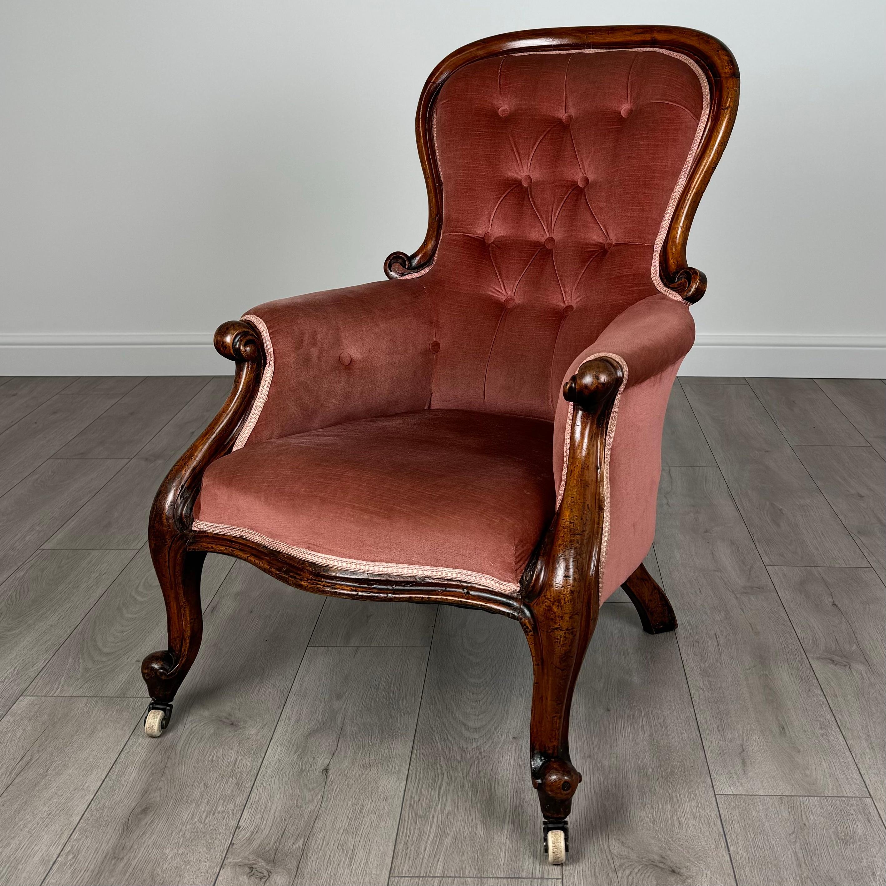 Este exquisito sillón con respaldo de botones del siglo XIX es un impresionante ejemplo de artesanía, fabricado en caoba de alta calidad. La silla se apoya en dos elegantes patas delanteras cabriolé, cada una de ellas con ruedas para facilitar su