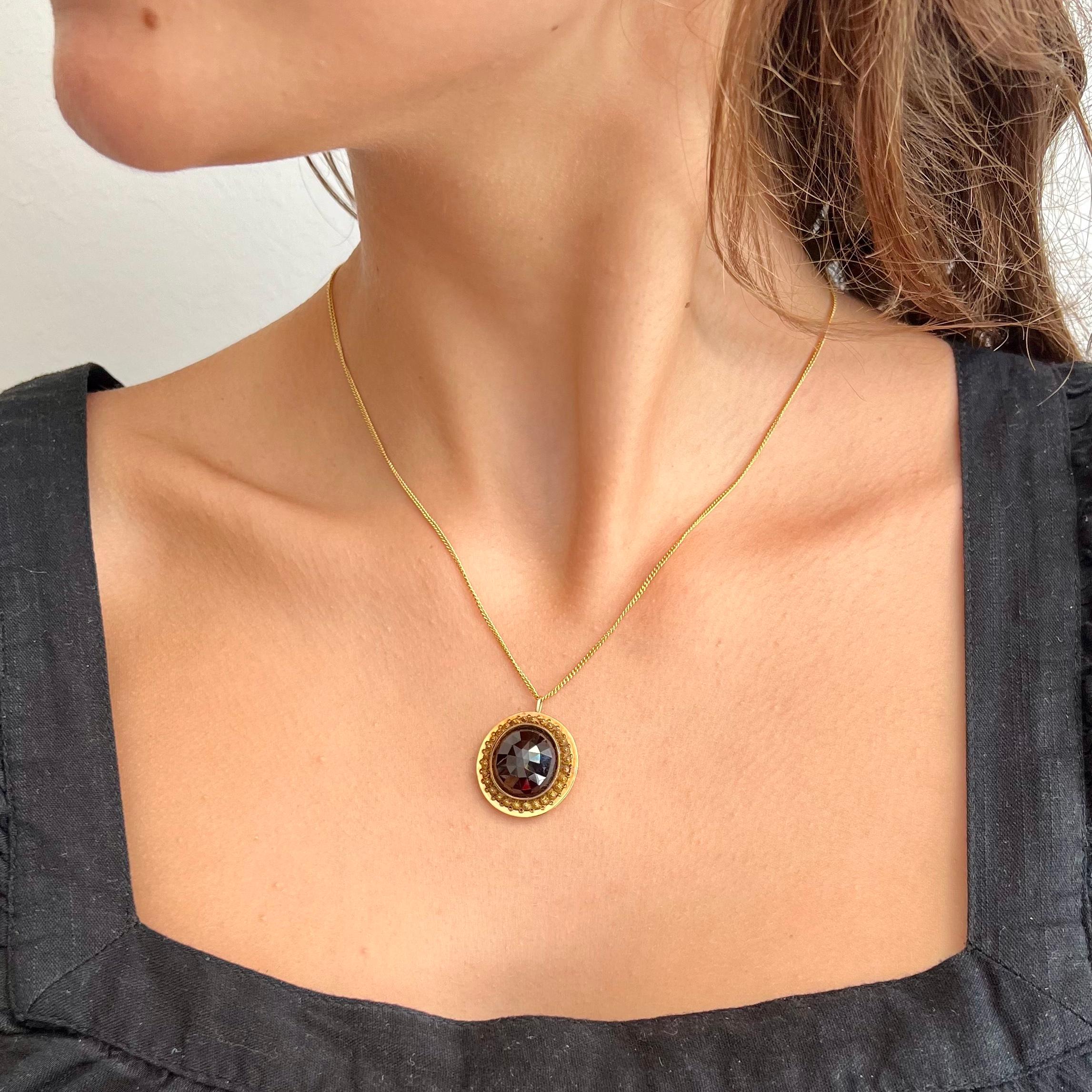 An antique 19th century gold cannetille pendant set with an oval-shaped faceted garnet stone. The cannetille work is delicately made by hand. In the Netherlands they also call these rosettes 'spiders', there is the spiders body in the center
