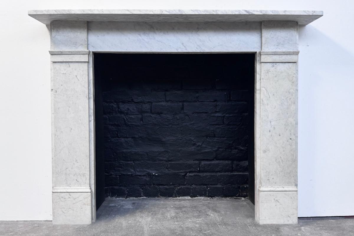 Antique 19th-century Carrara marble fireplace surround of simple form and good proportions. With unadorned square capitals flanking the frieze and above plain jambs. Circa 1880.

This fireplace is currently awaiting restoration. It is priced once