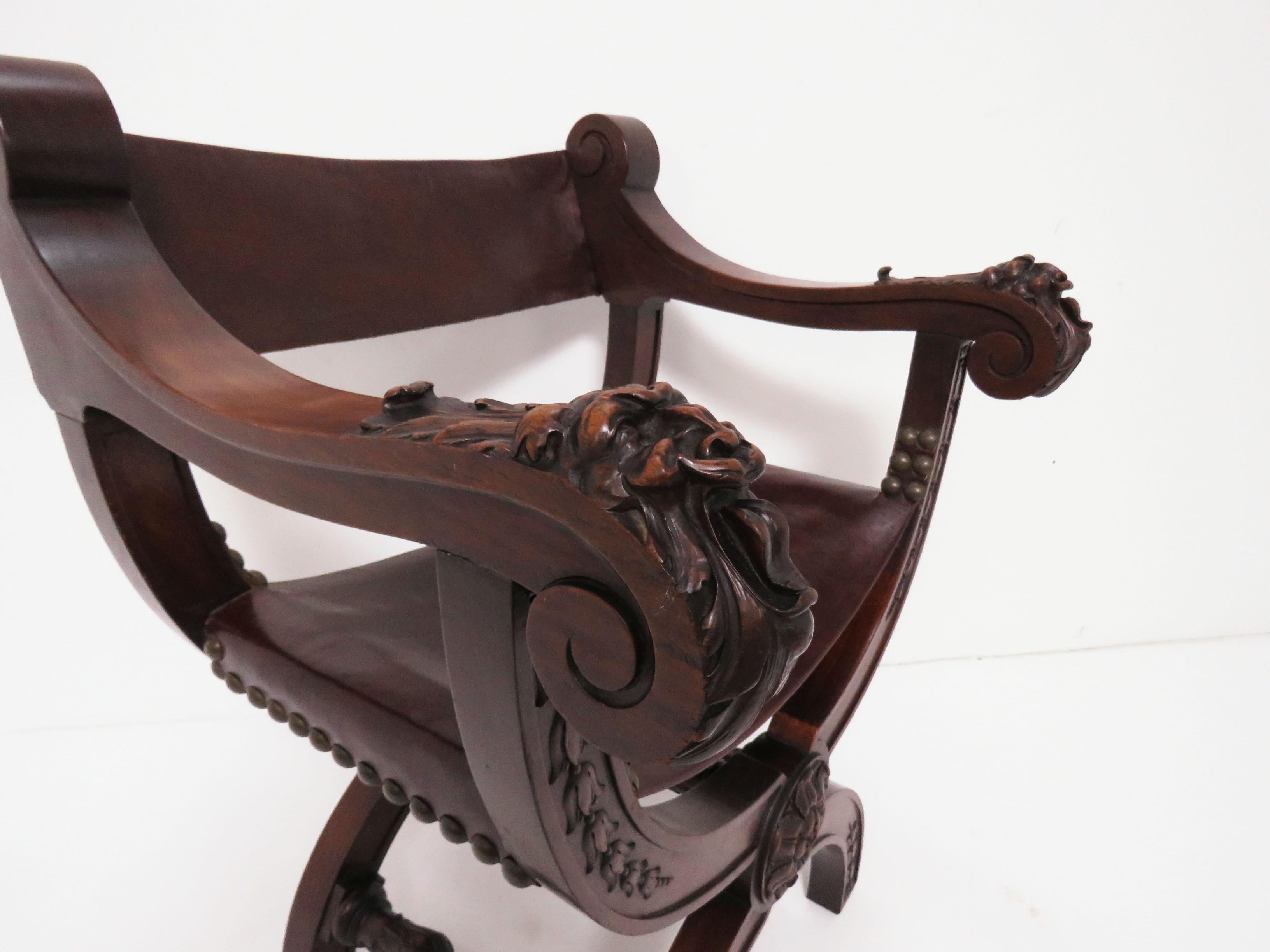 A late 19th century carved mahogany curule chair with sling seat and back in cordovan leather. Features fantastically carved griffins at the arm rests with bas-relief garlands to the lower portion, center medallion and heavily turned stretchers and