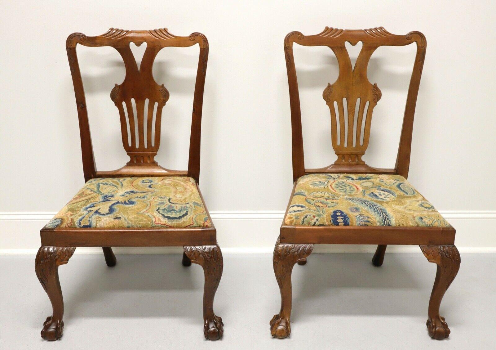 A pair of antique walnut dining side chairs in the Chippendale style, unbranded. Features carved backs, colorful needlepoint seats, cabriole legs with carved knees and ball in claw feet. Likely made in the USA, in the late 19th Century.

Measures: