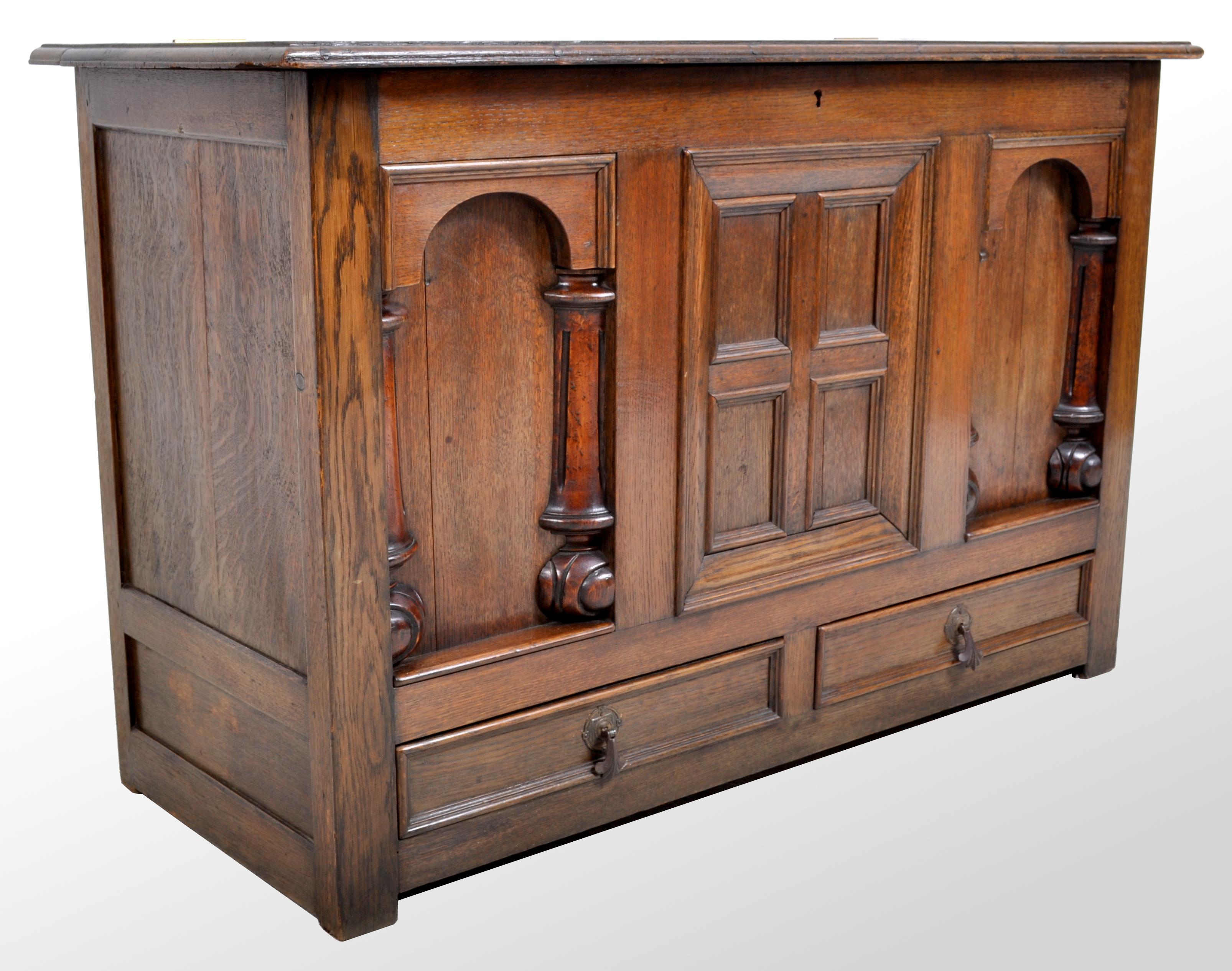 Antique 19th century carved oak mule chest/coffer, in the William & Mary style circa 1870. The coffer having a hinged lid above two arched panels with turned and quartered columns flanking a central fielded panel. Below are two drawers with brass