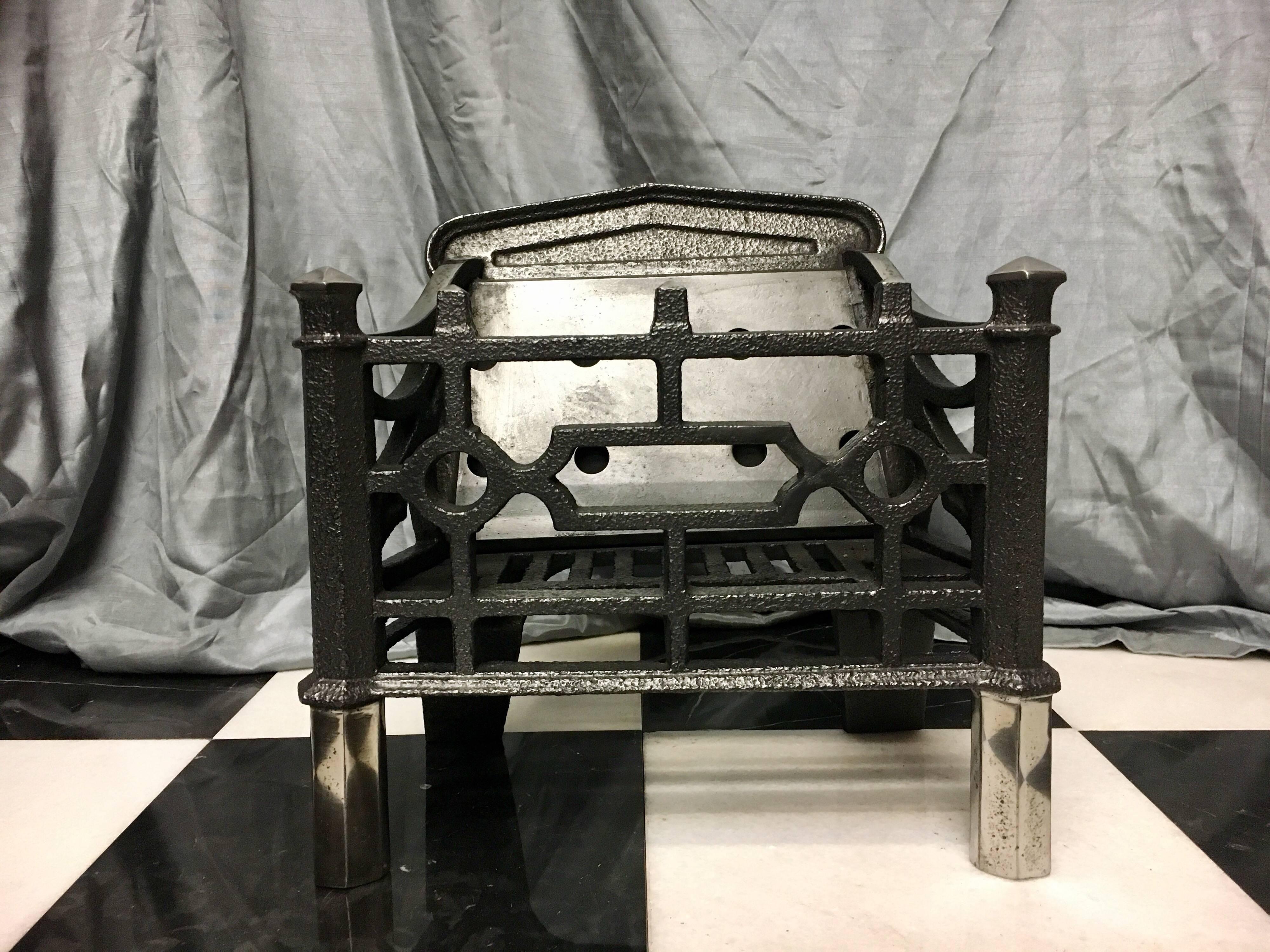 A petite French antique early 19th century cast iron fire basket in the Gothic manner, a shaped back with original steel heat plate, linked circles to the front instead of fire bars.
French, circa 1840.