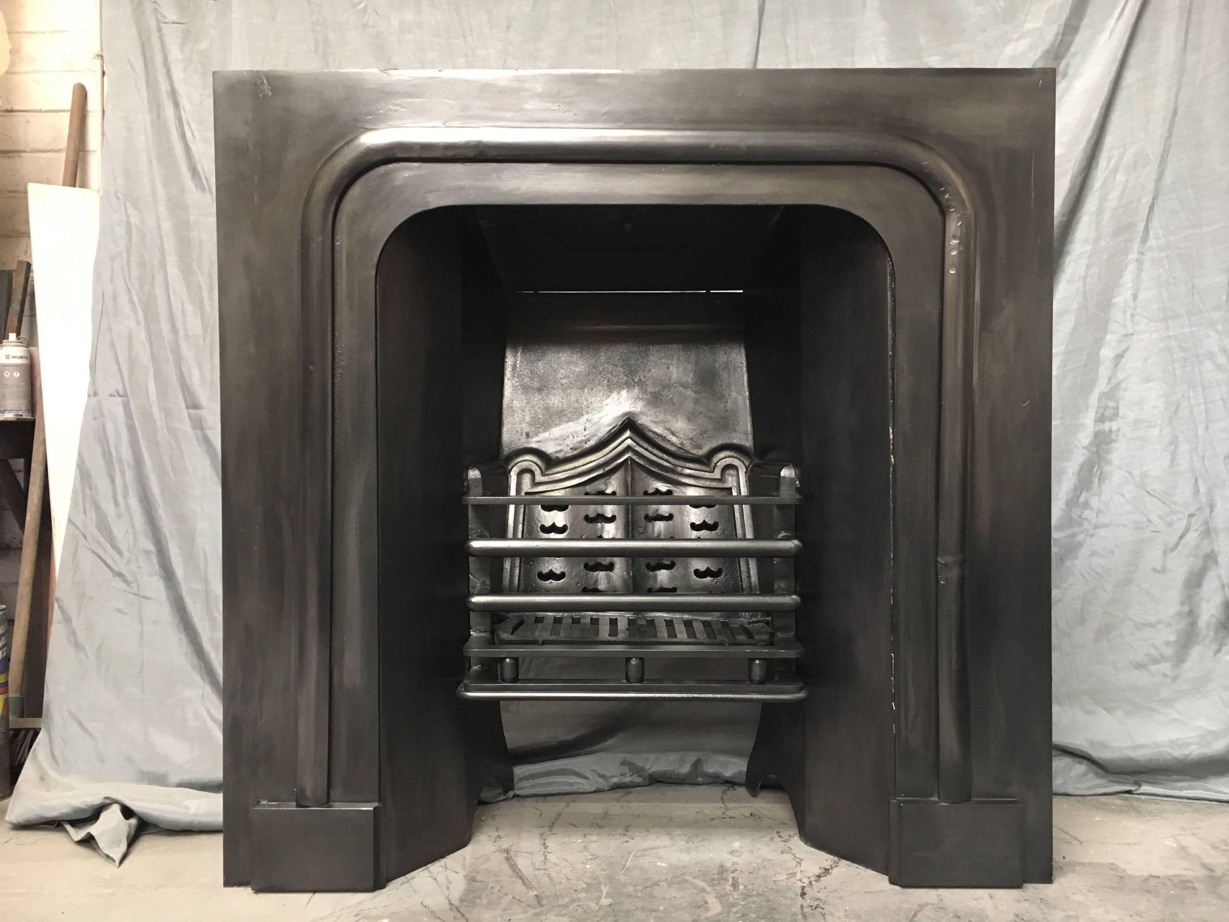 A masculine Antique 19th century cast iron Gothic style fireplace insert cast by the Carron foundry, a five bar grill with baseline cushion spaces, sits central with a Gothic shaped heat plate behind. A good sized piece with historical metal work to