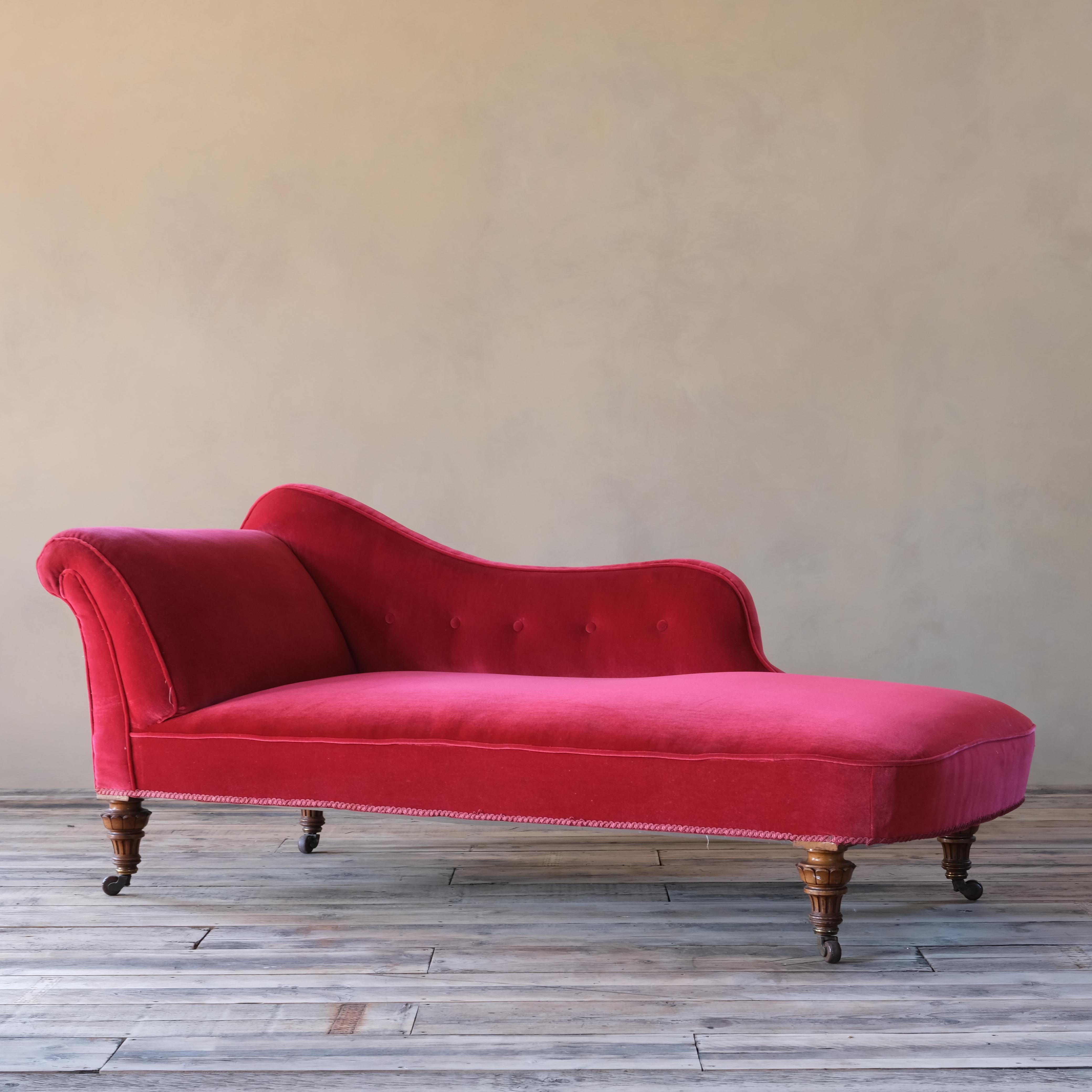 A very well formed 19th century chaise lounge raised on 4 walnut legs that are of the finest quality with the original casters. The upholstery is a deep red velvet that does show signs of wear but is usable however upholstery. 

structurally sound