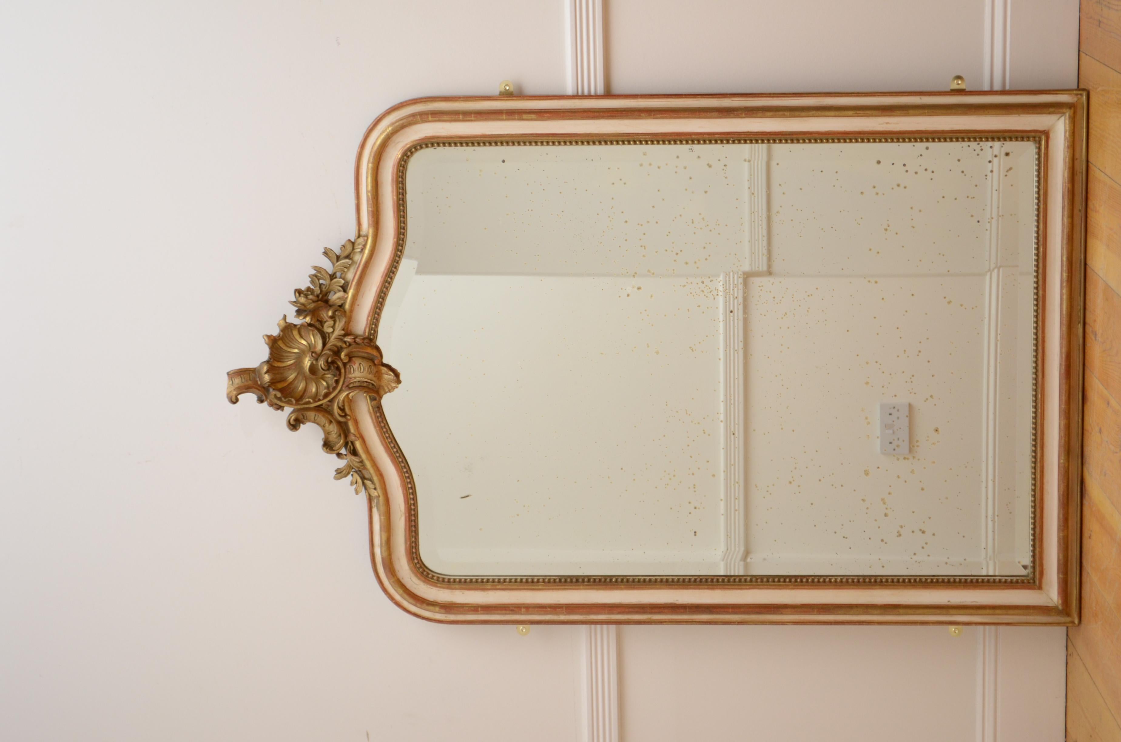 K0467 Precioso espejo de pared francés, de color crema y pan de oro, con cristal biselado original con abolladuras, marco de cuentas y perfilado con concha y elaborada cresta floral central en la parte superior. Este espejo antiguo conserva su