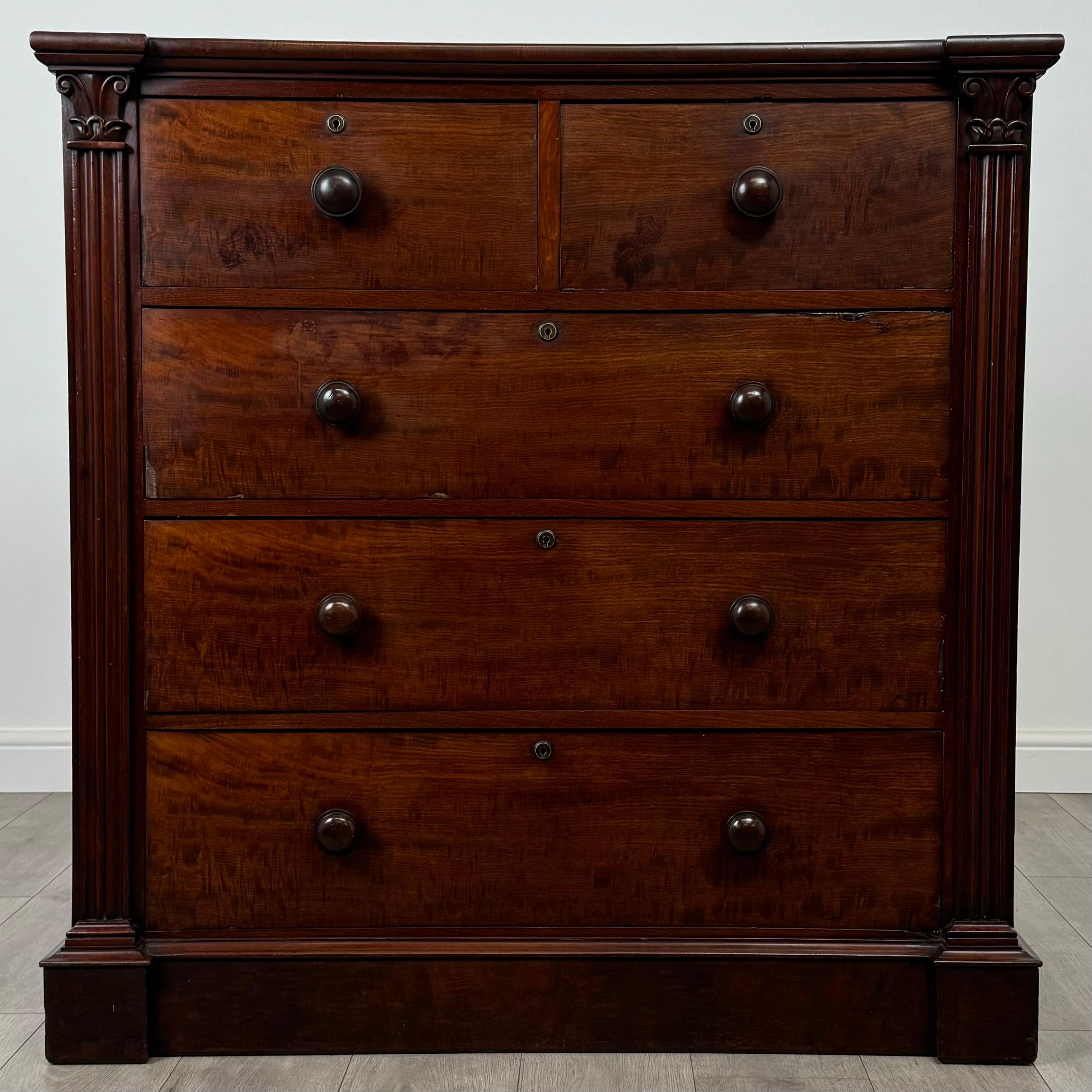Cette ancienne commode du XIXe siècle, fabriquée en acajou, présente un très beau et unique design qui en fait une pièce à part. Posée sur un socle solide, la commode offre cinq tiroirs au total, répartis en deux petits tiroirs sur trois plus